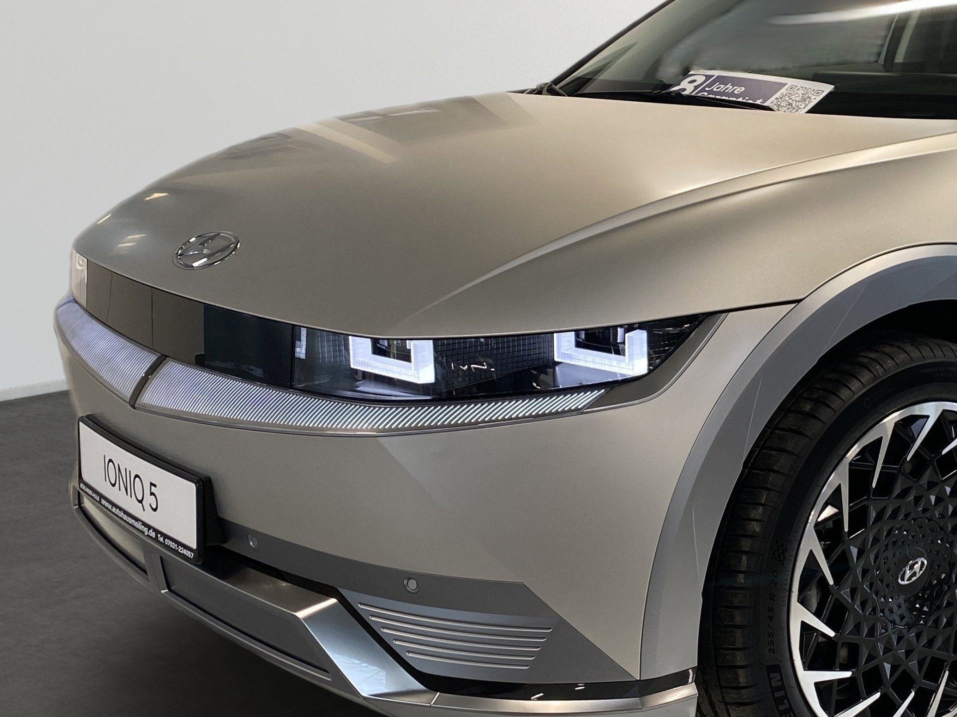 Close-up of a silver-gray sports car front with sleek headlights and a black grille