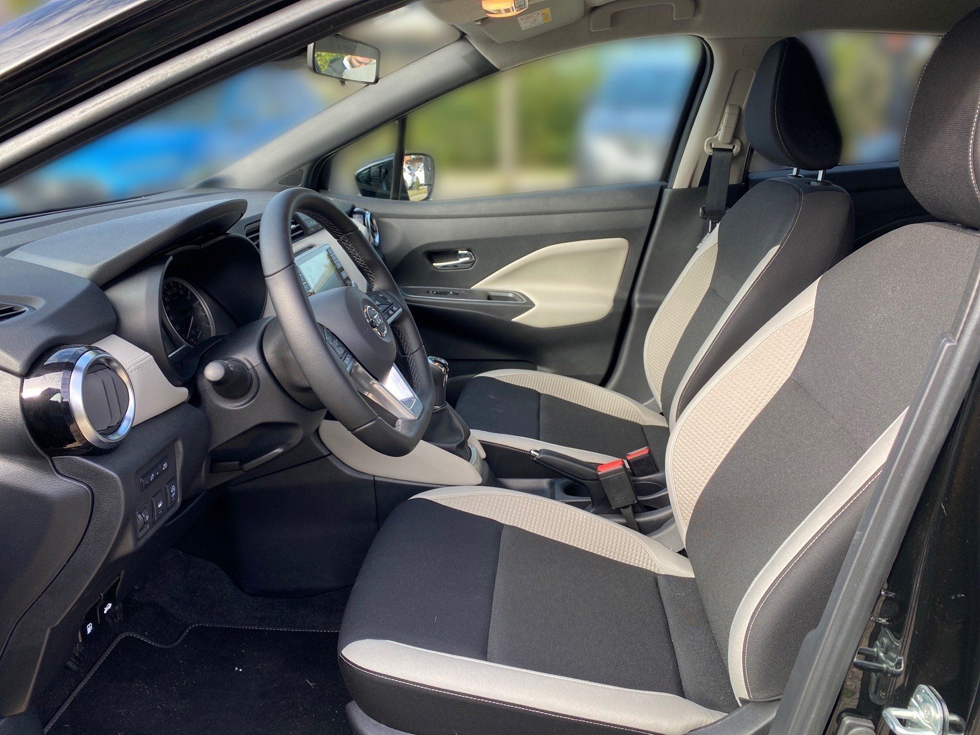 Der Innenraum eines schwarzen Autos mit Lenkrad und Sitzen, der Blick durch die Fenster ist mit Unschärfe verschwommen.