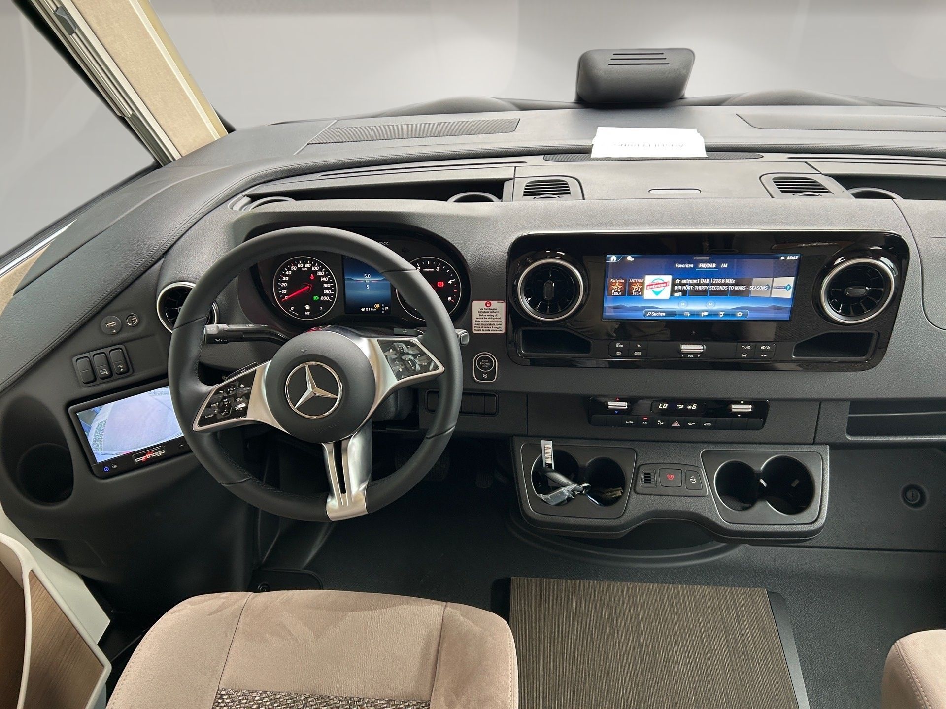 Kokpit dodávky Mercedes-Benz s volantom, displejom na palubnej doske a béžovými vnútornými sedadlami
