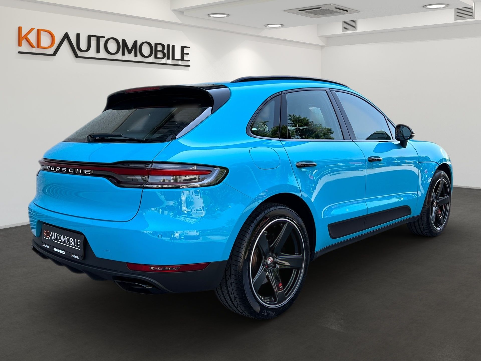 Bright blue compact SUV in a showroom, rear three-quarter view, with KD Automobile sign on the wall