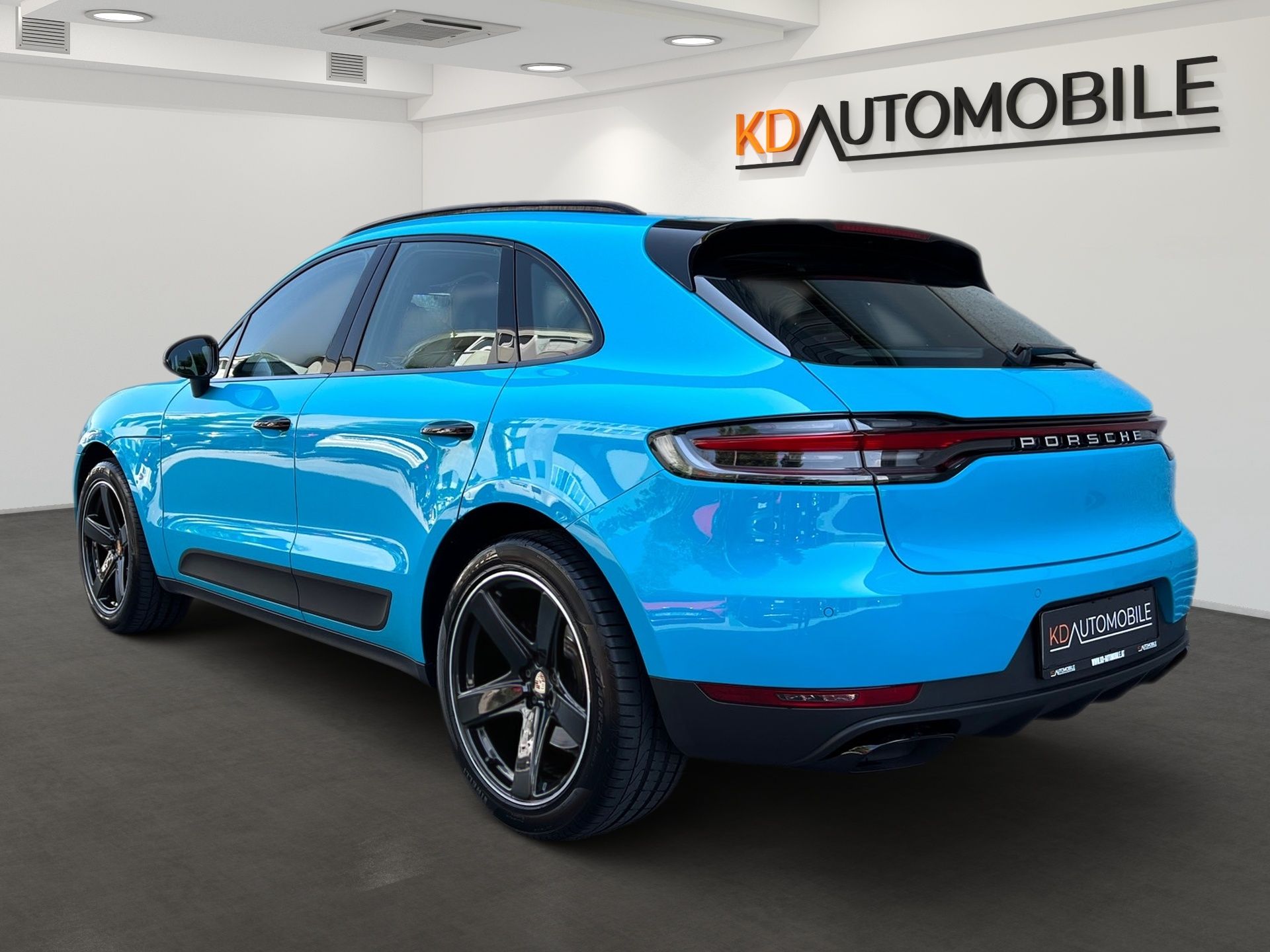 Bright blue SUV in a showroom, rear three-quarter view, with KDAutomobile sign in the background