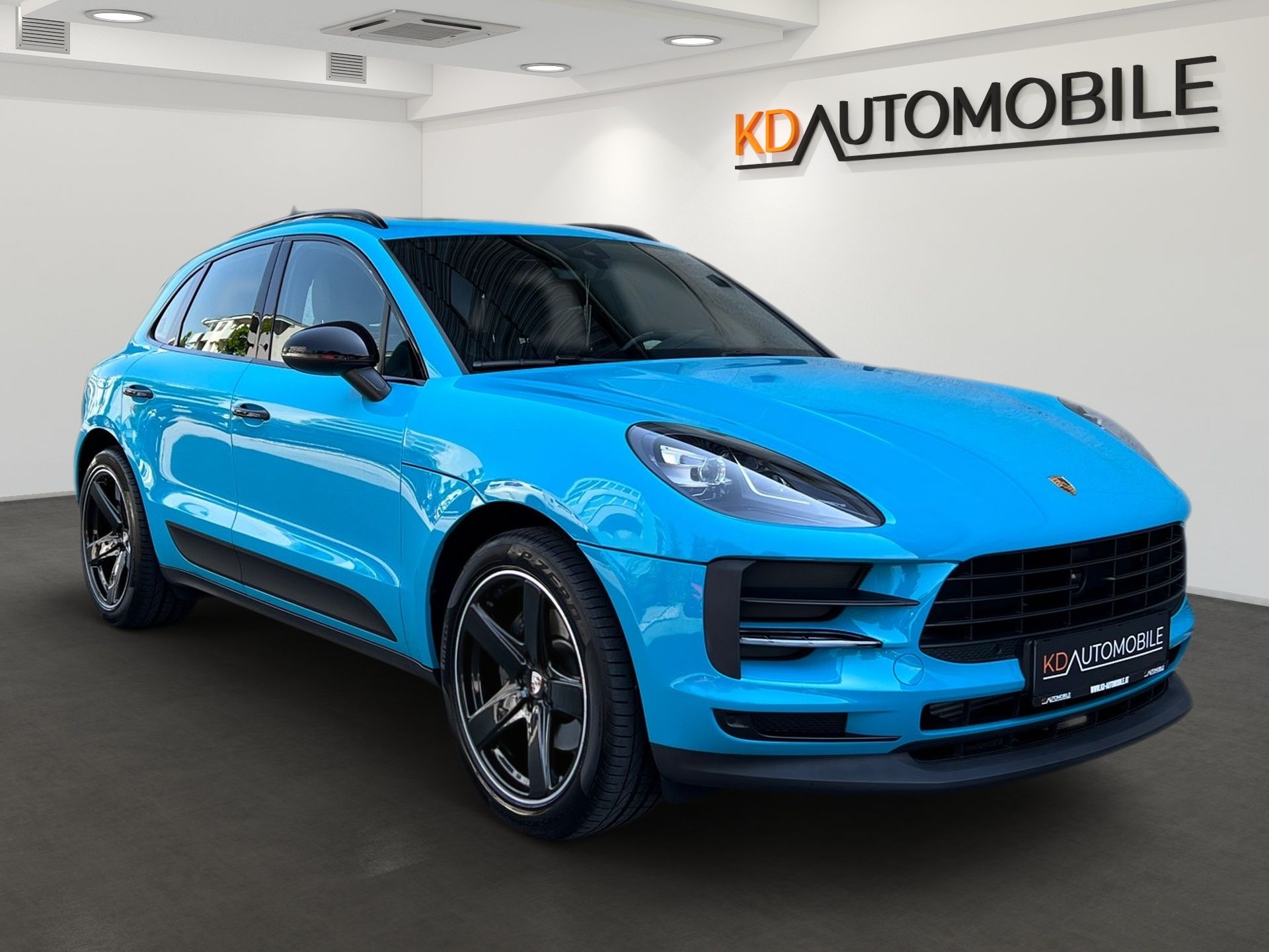 Blue Porsche SUV in a showroom with K&K Automobile signage on the wall