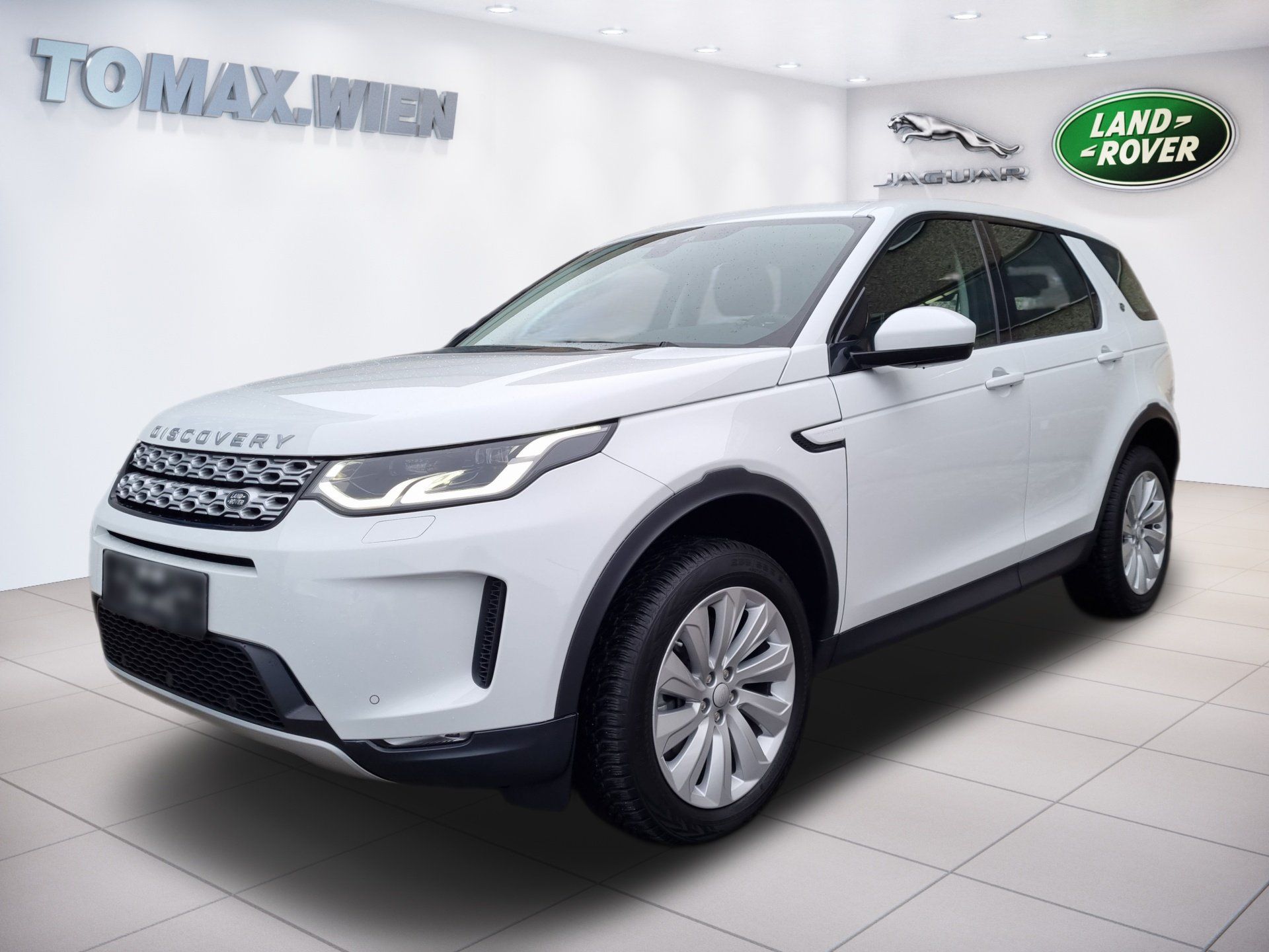 Biele SUV v showroome, pohľad spredu pod uhlom s nápisom TOMAZIND na stene