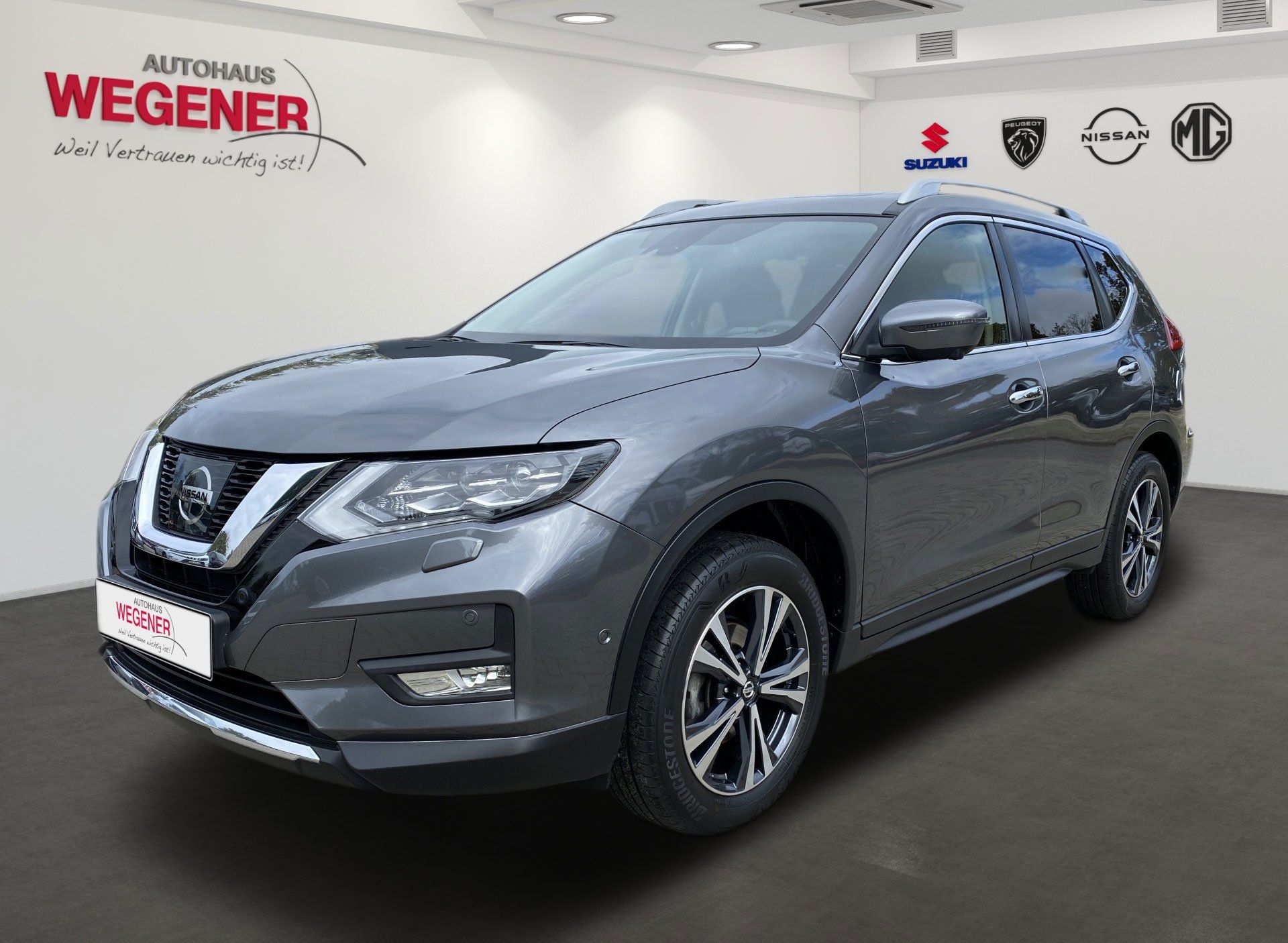 Sivé SUV Nissan v showroome s logom Wegener na stene