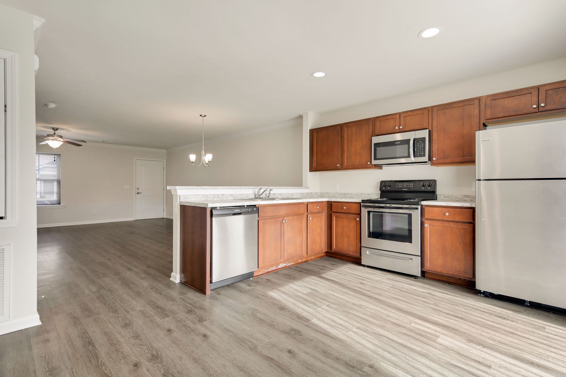 A kitchen with wooden cabinets , stainless steel appliances , and a refrigerator.