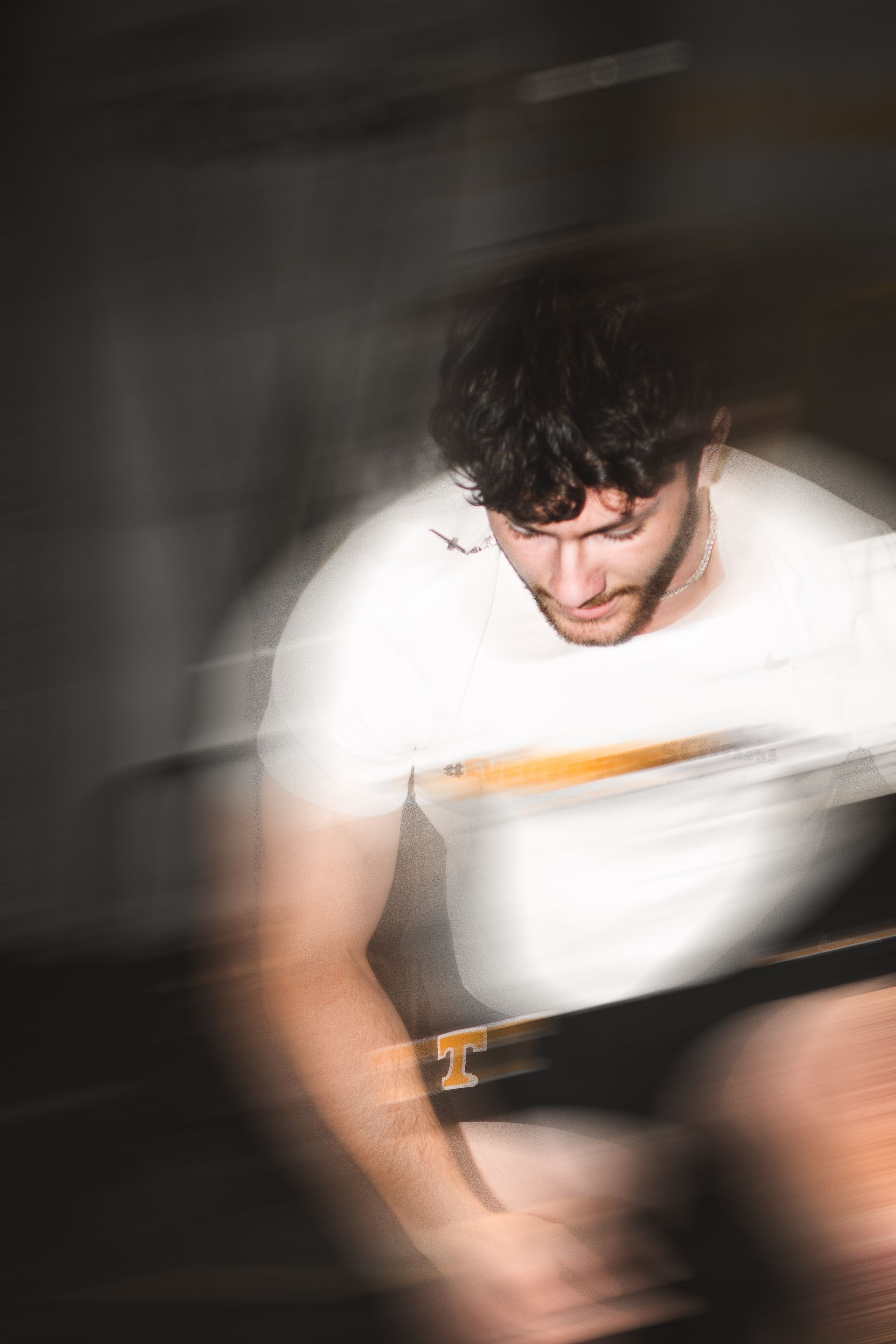 Blurry motion shot of a person in a white shirt and black shorts bending forward indoors