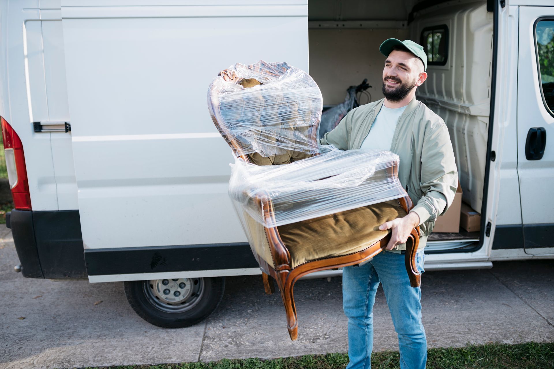 A furniture removal worker arriving at a new home with a shrink-wrapped sofa chair.