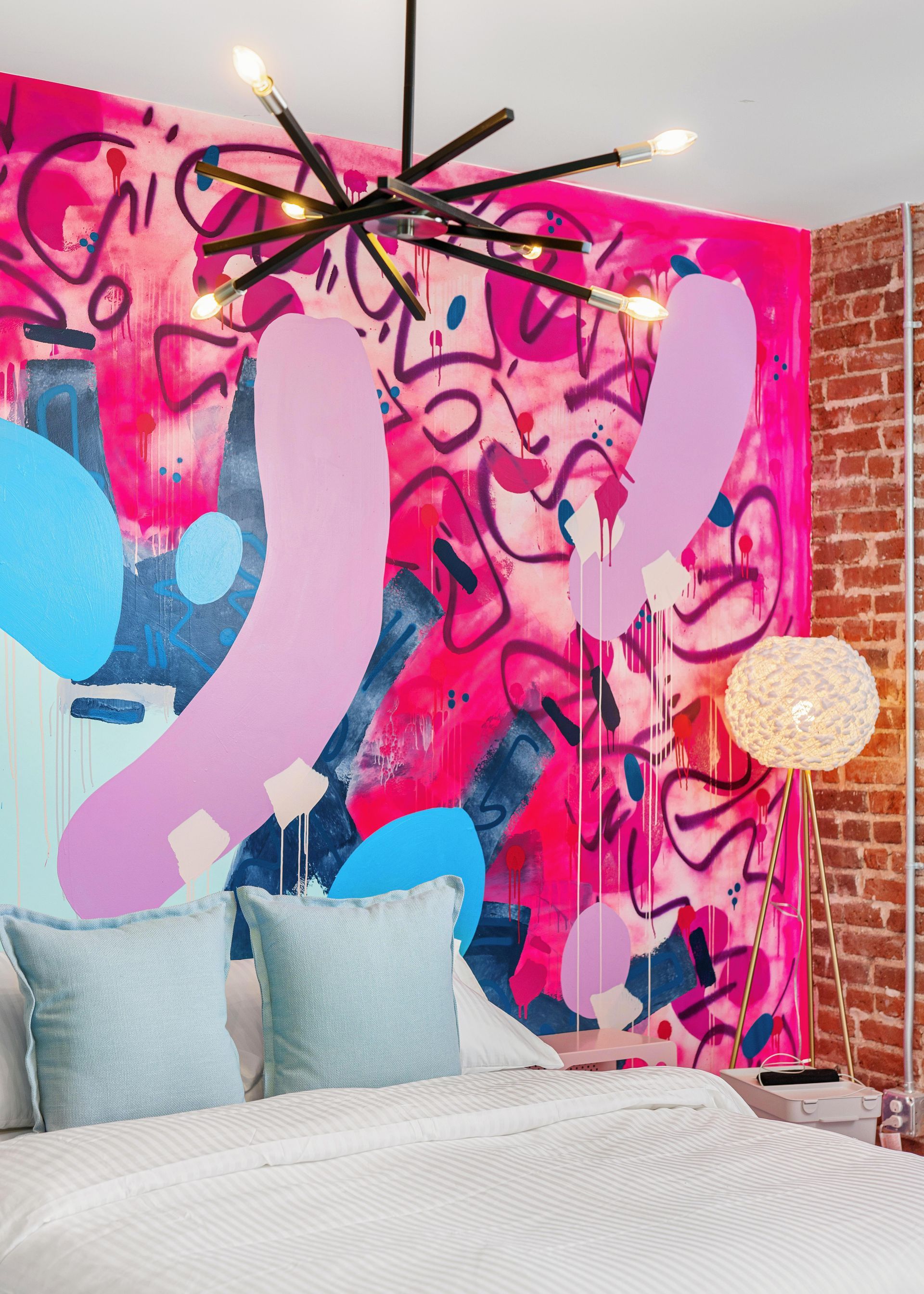Modern bedroom with a vibrant pink-and-blue abstract mural behind the bed