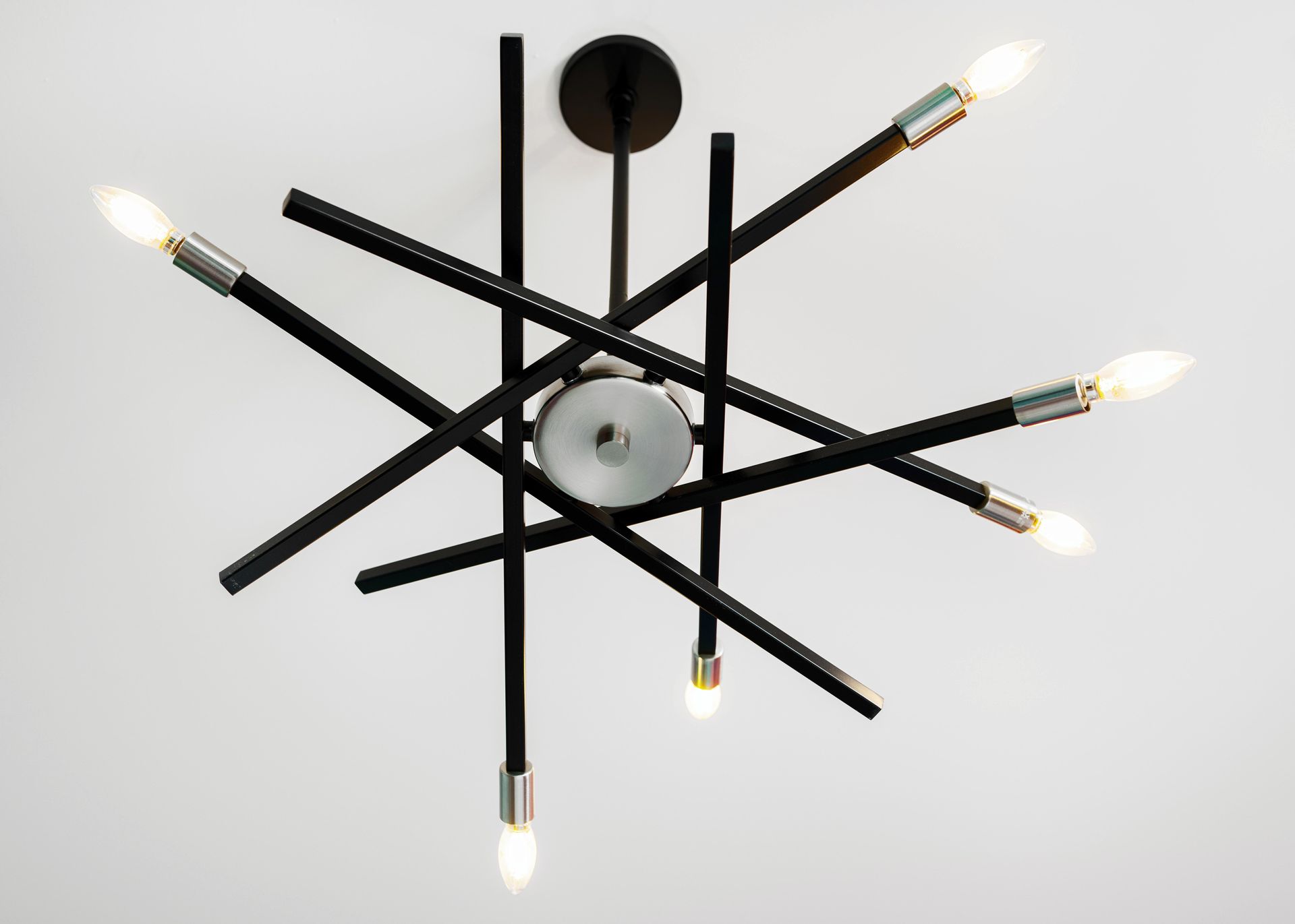 Black multi-arm ceiling light fixture with exposed bulbs on a white ceiling