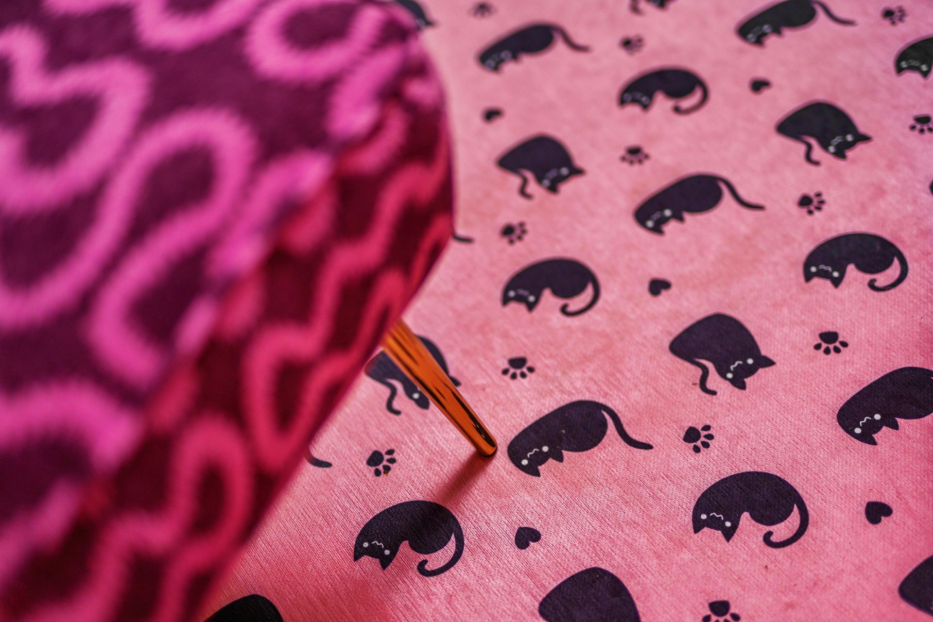 Close-up of pink patterned fabric with a sewing needle pinned in it