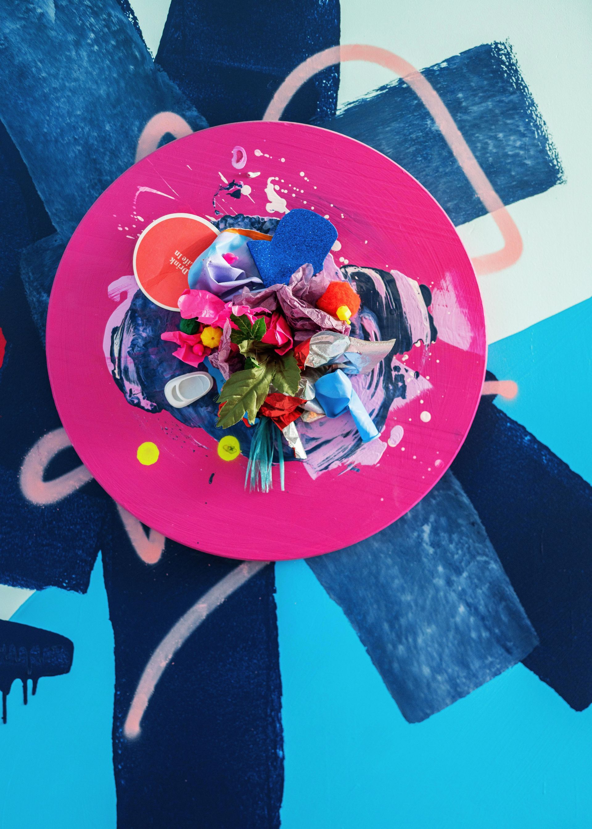 Bright pink circular artwork with colorful abstract collage on a blue and dark background