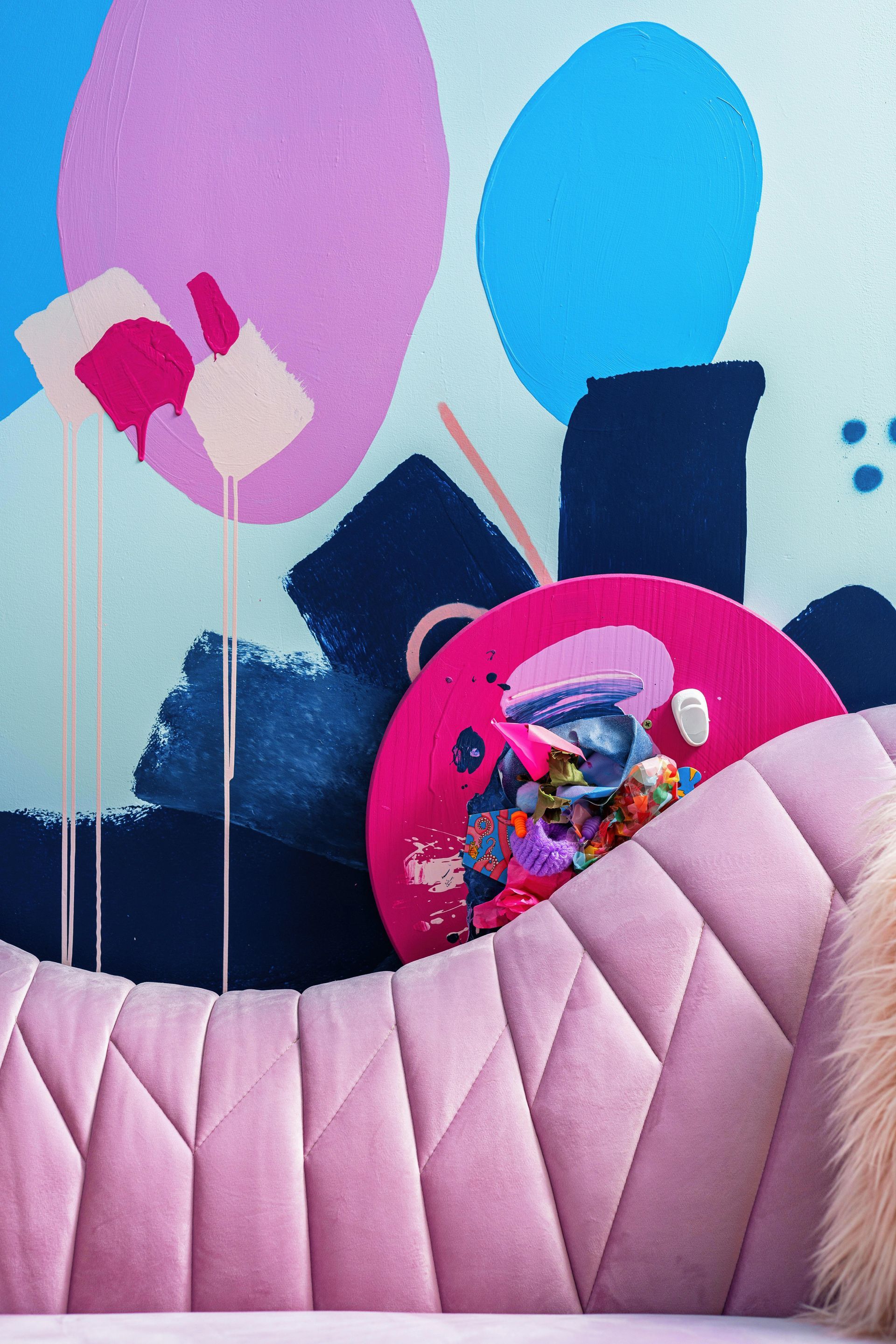 Pastel nursery mural with balloons, a quilted pink wall, and a round pink pocket holding toys