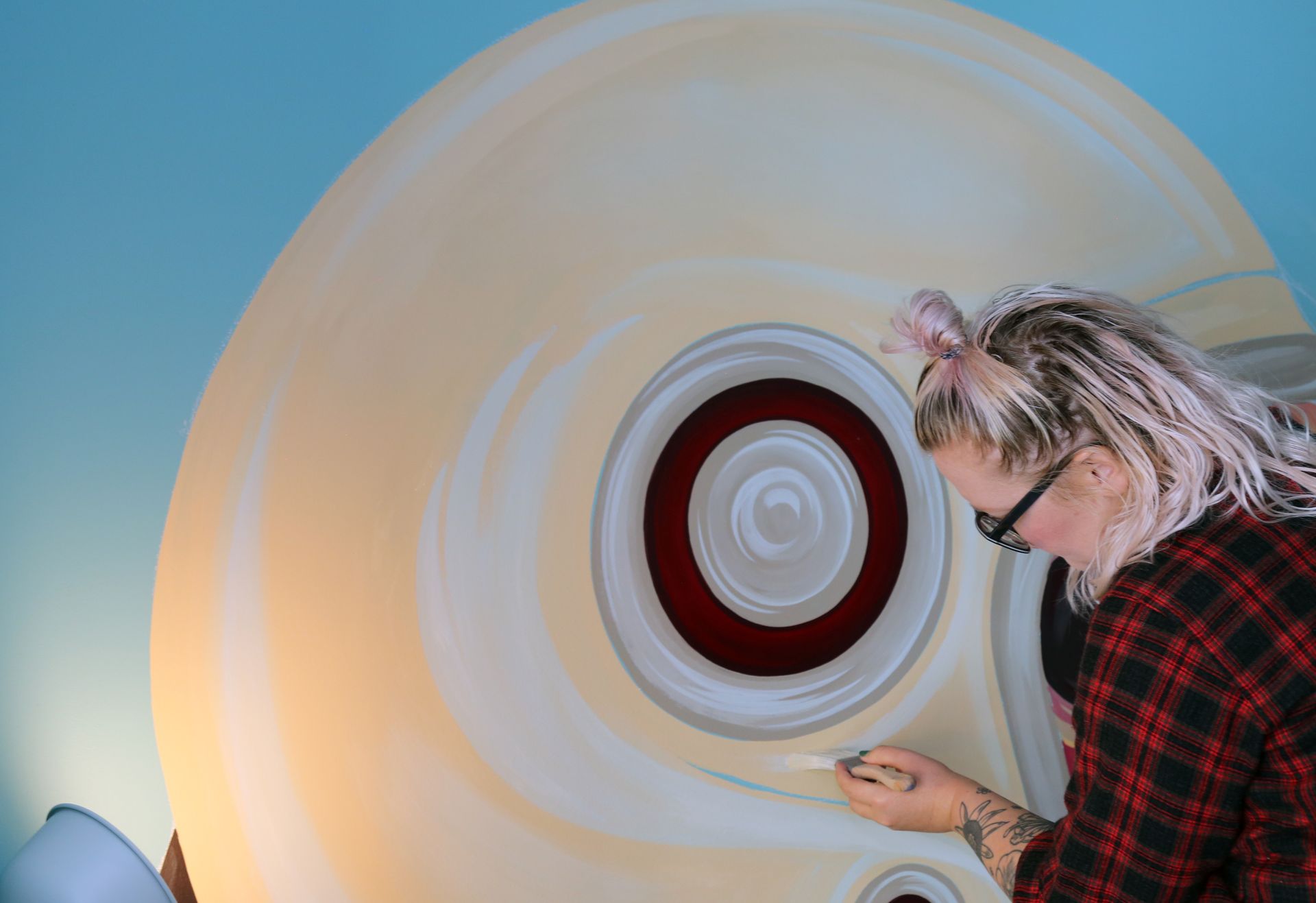 Person in red plaid shirt examining a large cream-colored circular surface with a red center