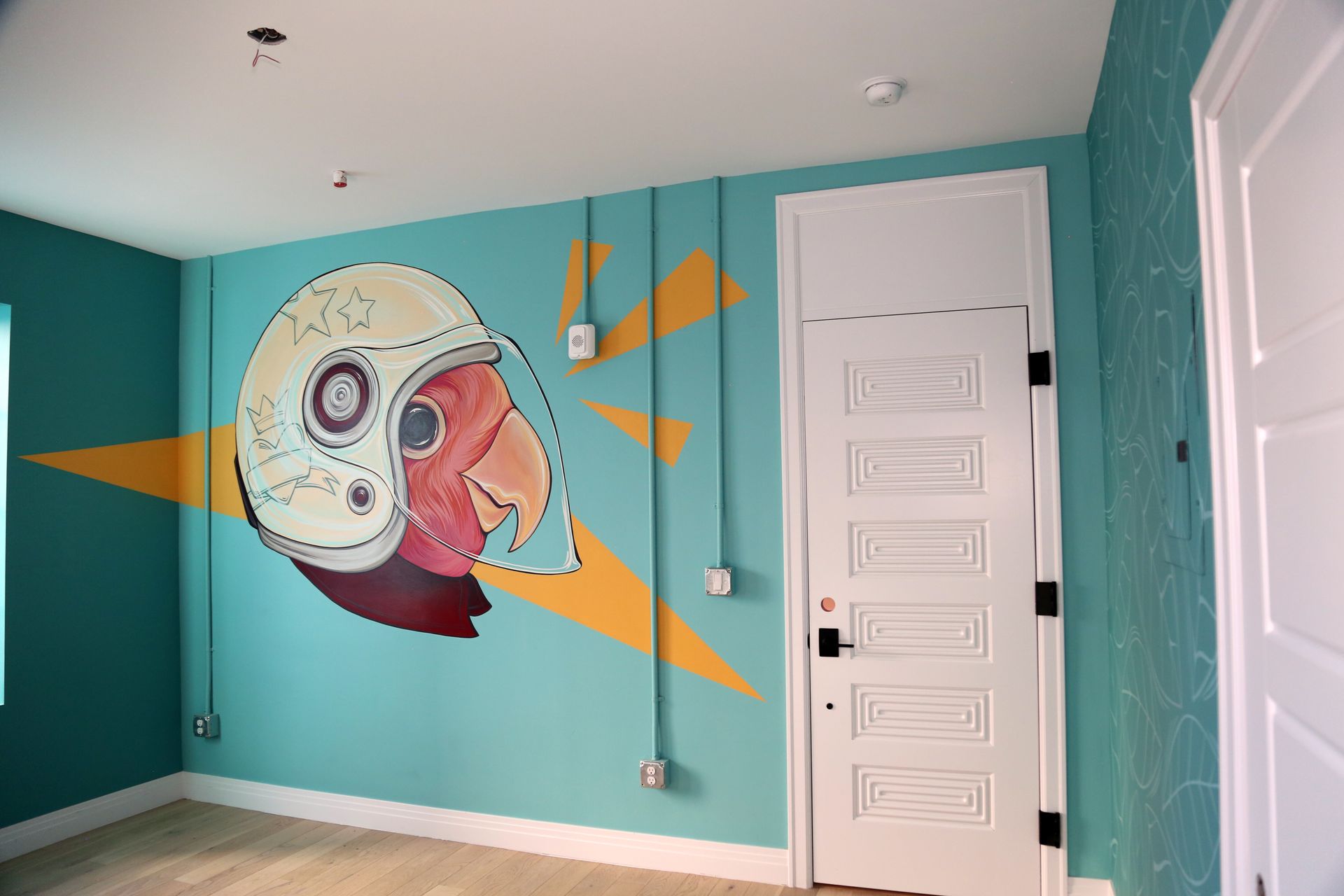 Teal room with a large colorful mural on the wall and white doors.