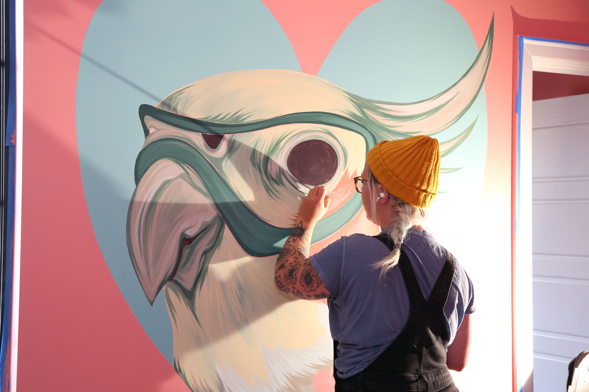 Artist painting a colorful mural of a dolphin on a wall indoors