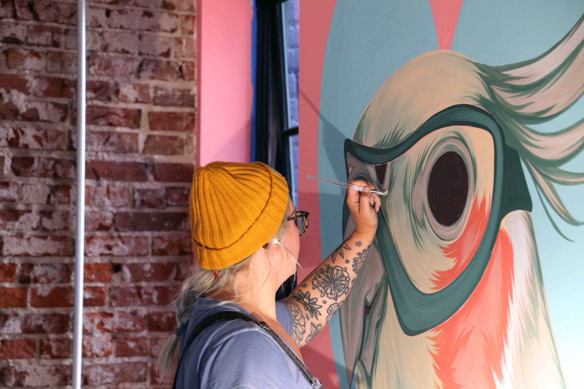 Artist painting a colorful mural of a large eye on a wall indoors