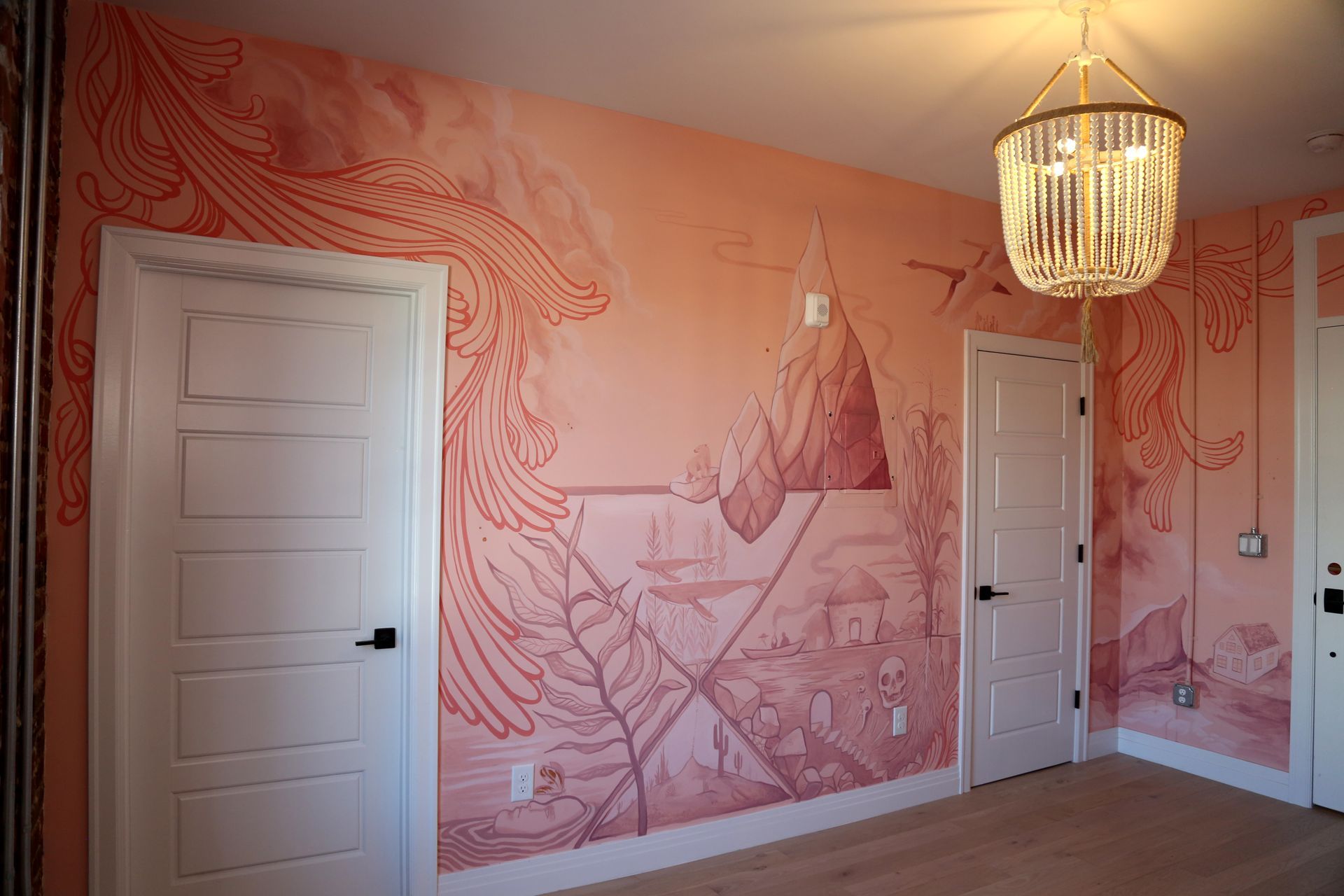 Pink mural-covered room with two white doors and a hanging chandelier