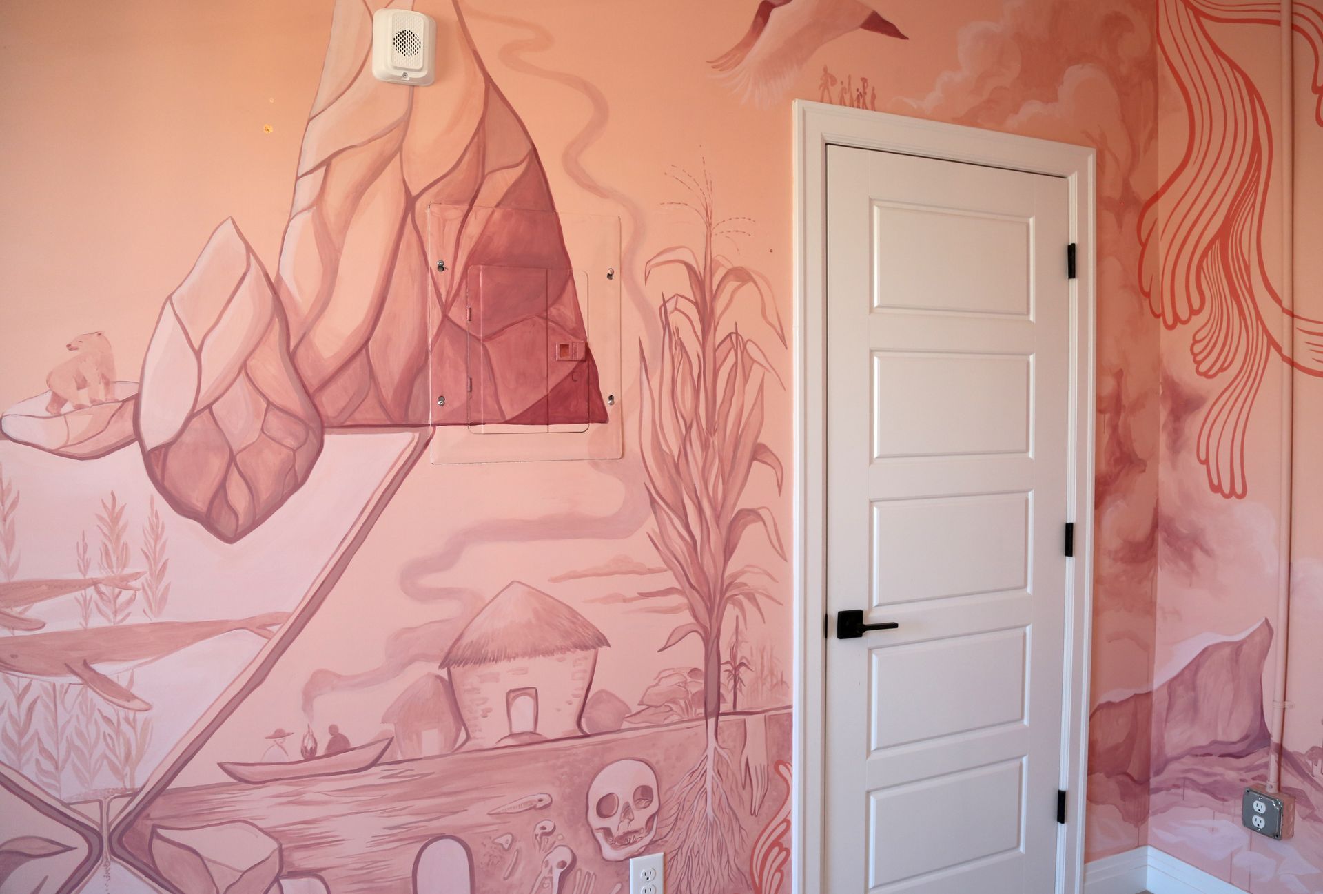 Pink mural-covered room with a white door and hand-painted plants and mountains on the wall