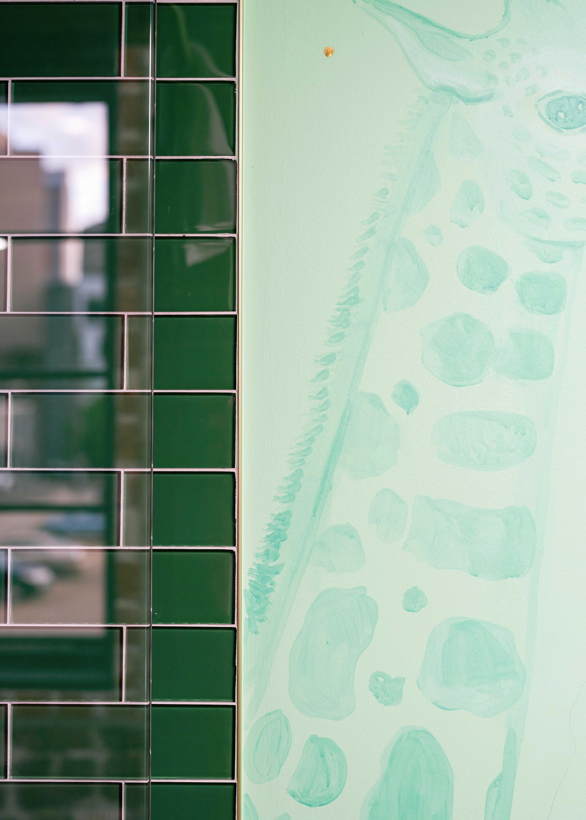 Green tiled wall beside a pale mint textured surface with faint circular patterns