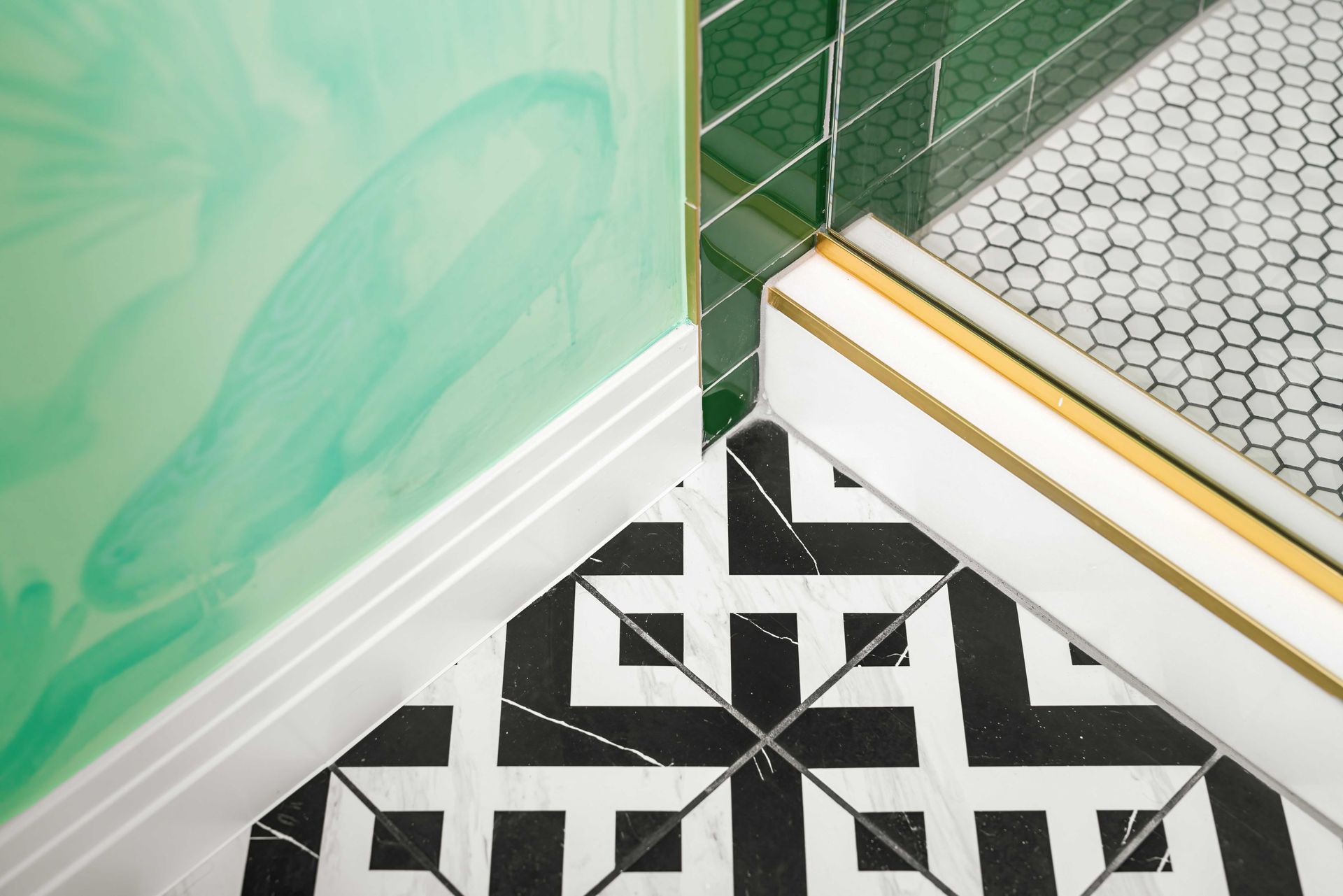 Black-and-white geometric tile floor beside green wall, white trim, and green-and-white hex tile step