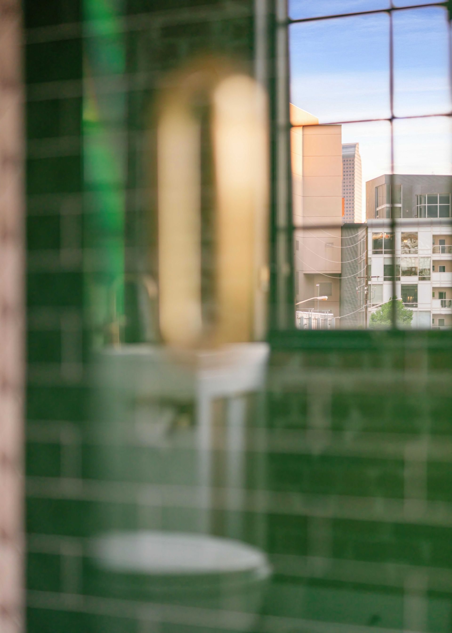 Blurred room interior with green-tiled wall and window view of buildings outside