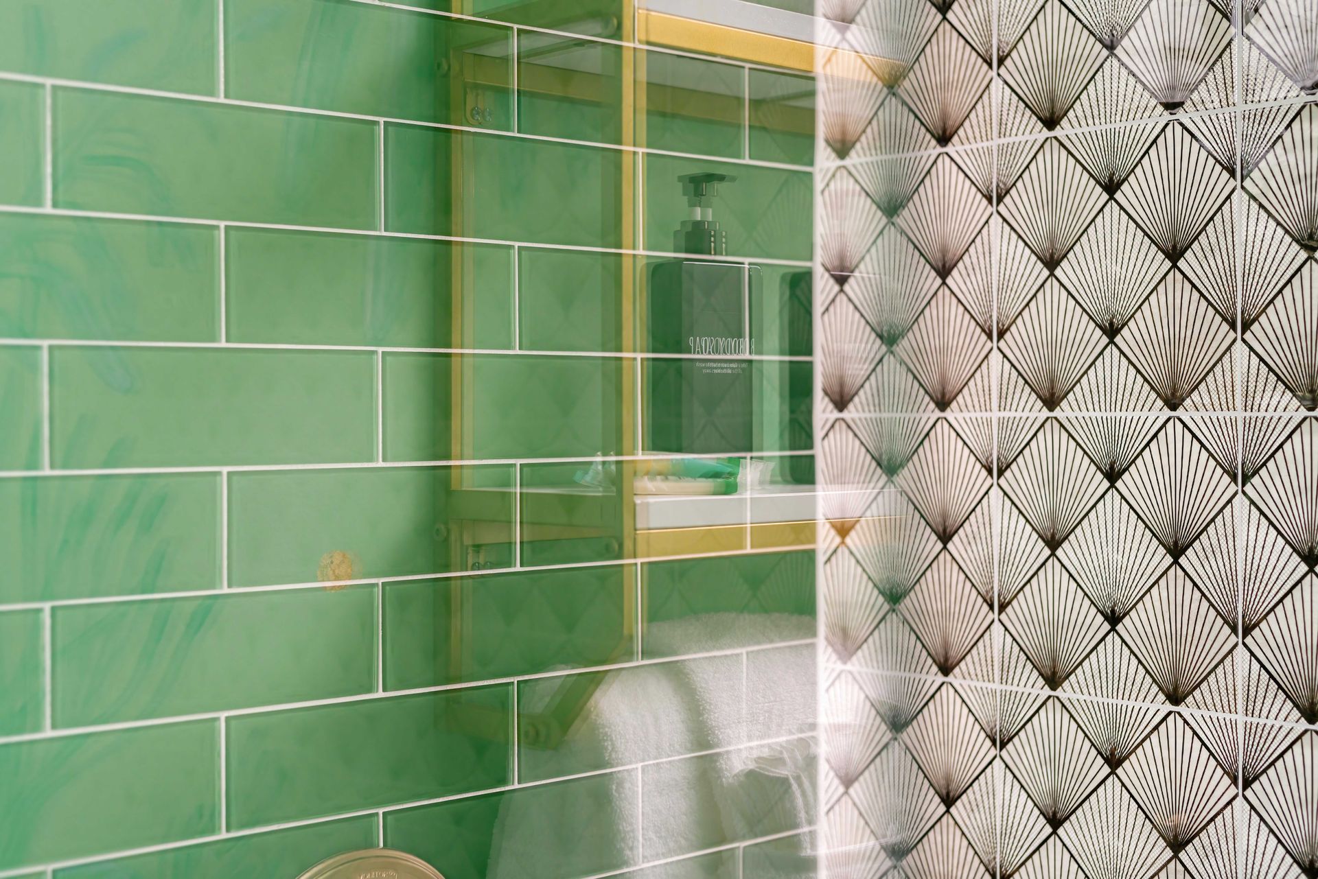 Green tiled bathroom with glass shower and patterned wallpaper edge