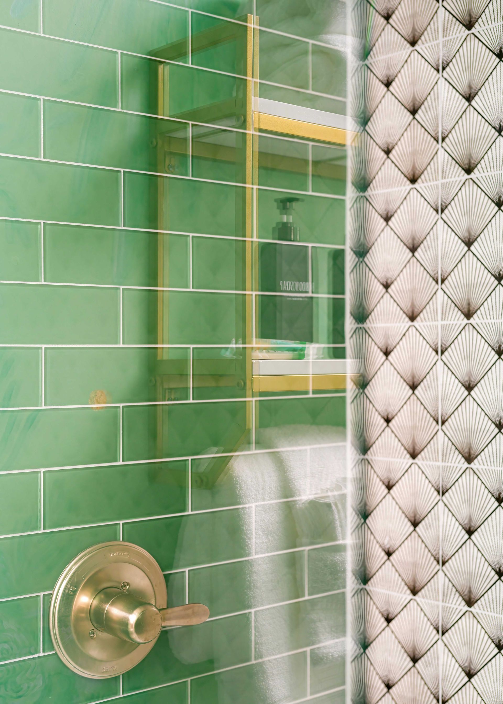 Green tiled shower with brass handle and frosted glass next to white quilted wall tiles
