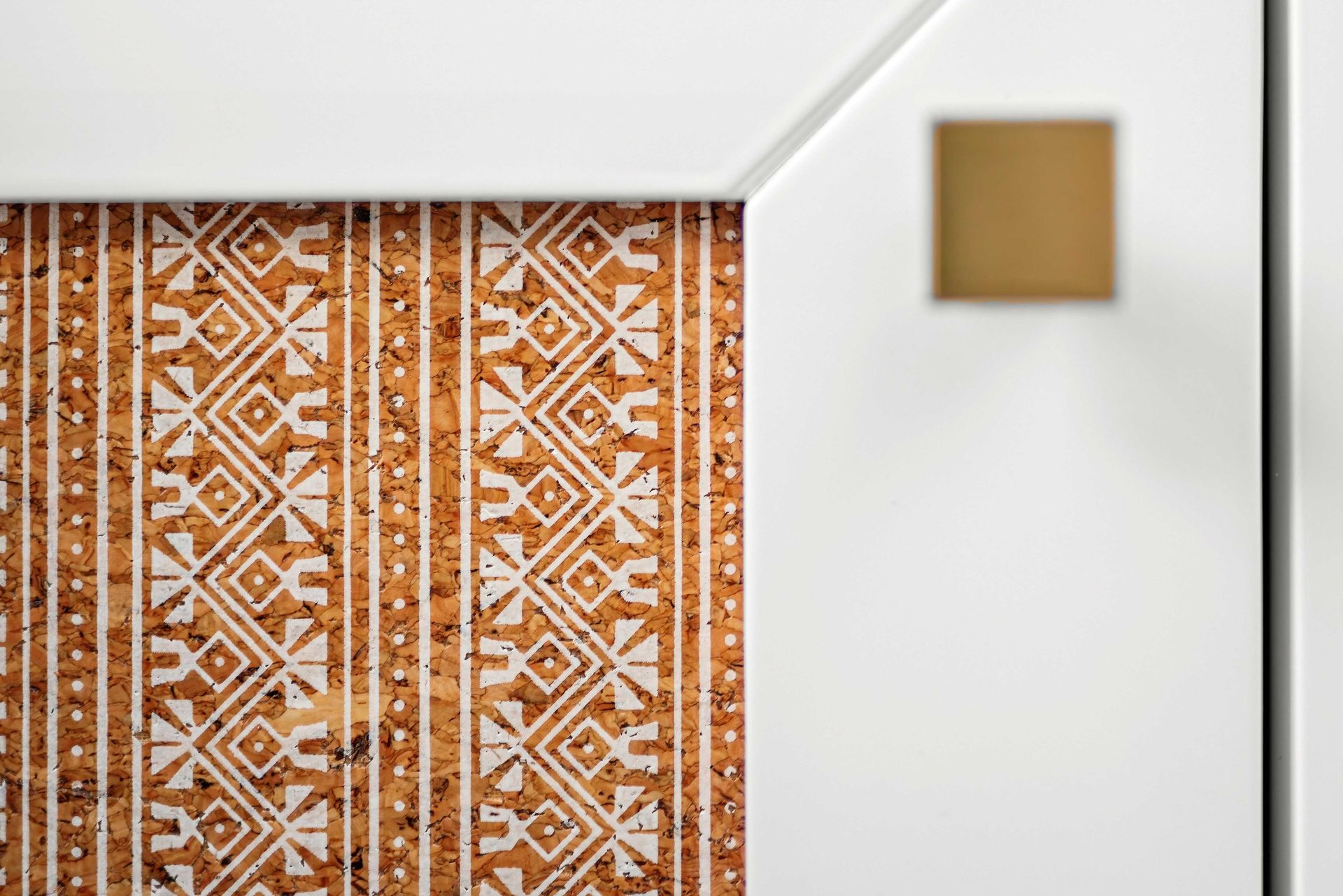 White wall with a square gold accent and an orange patterned hanging panel on the left
