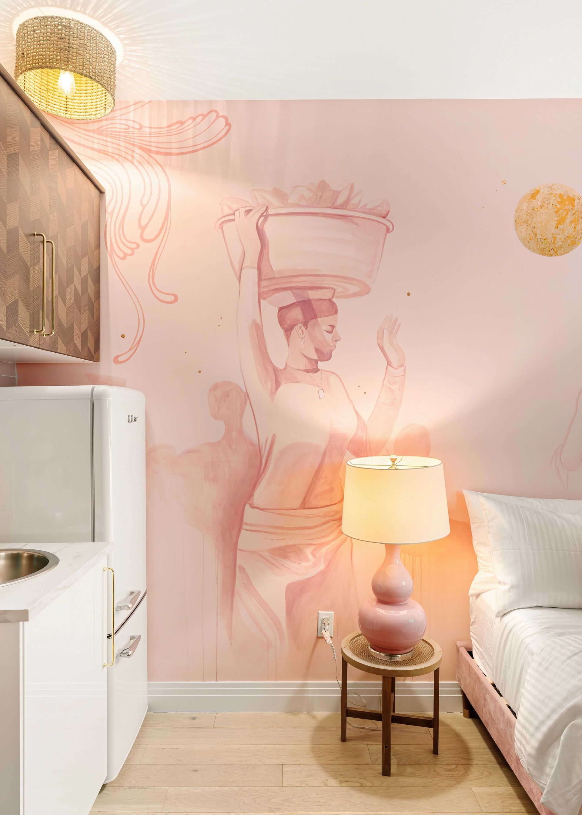 Pastel bedroom with mural wall art, lamp on side table, white bed, and mini fridge in the corner