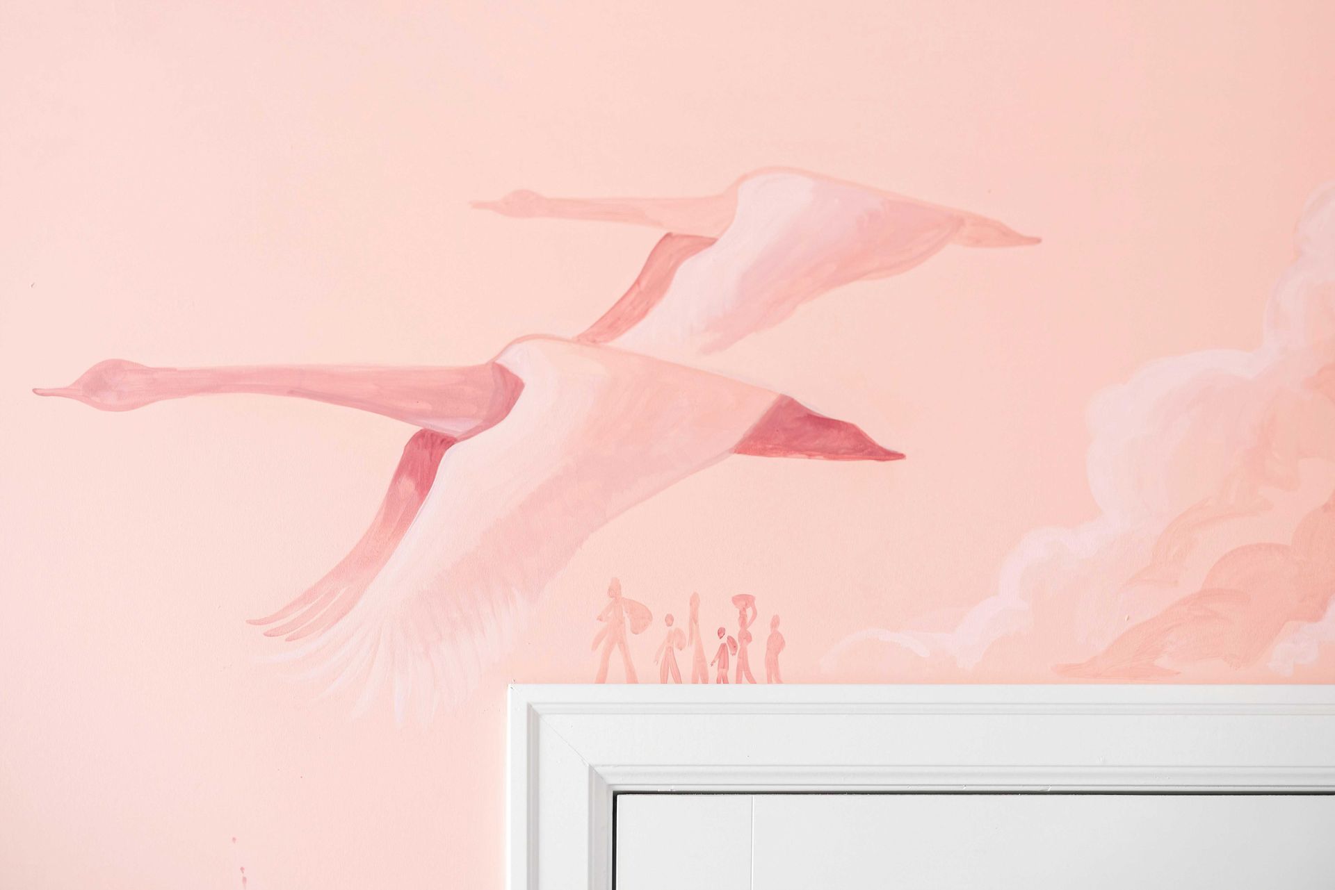 Pink wall mural of flying birds above a white doorframe