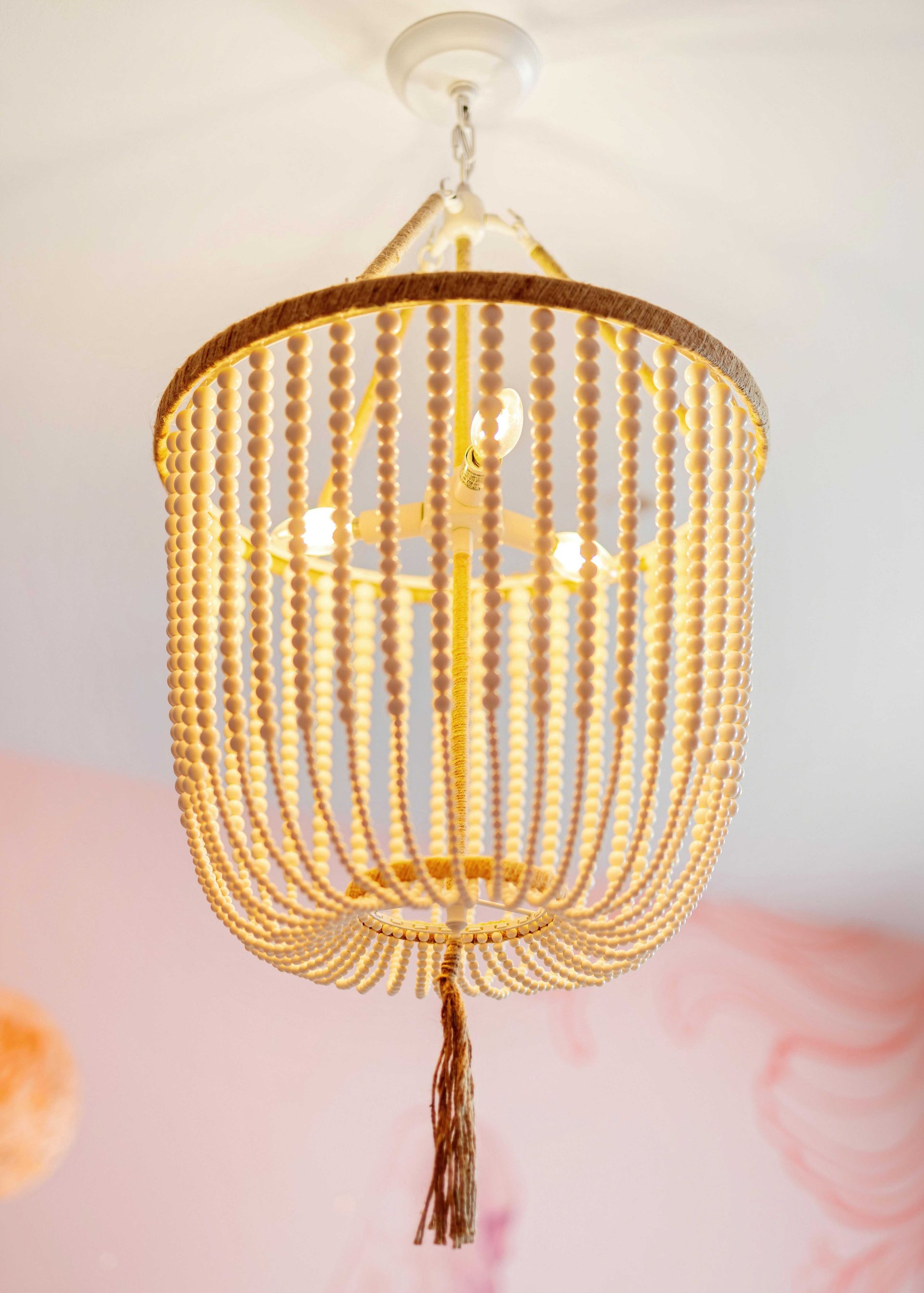 Gold beaded chandelier with tassel hanging from a white ceiling
