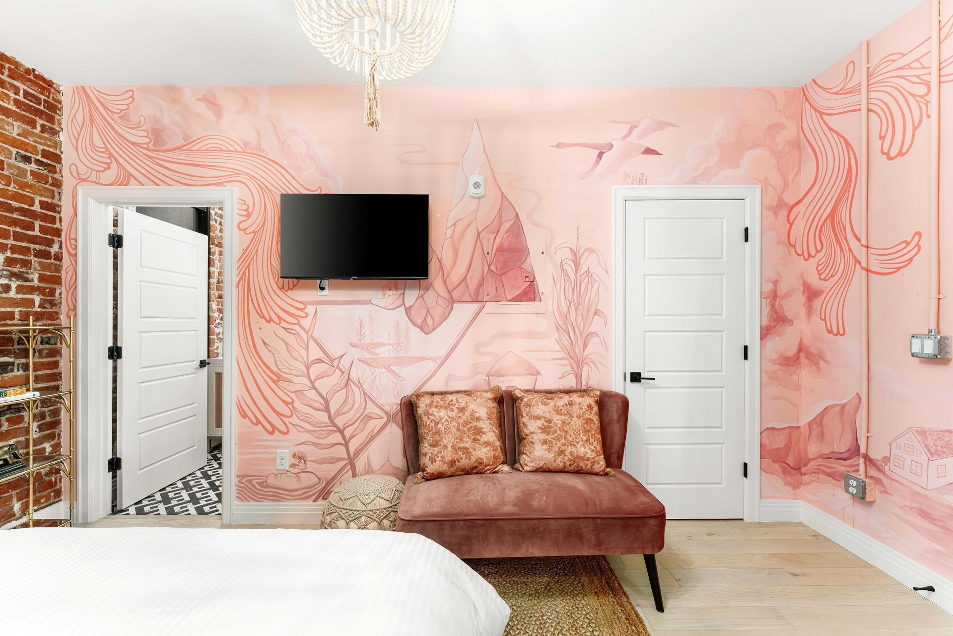 Pink bedroom with floral wall mural, TV, chaise lounge, mirrored closet, and white doors