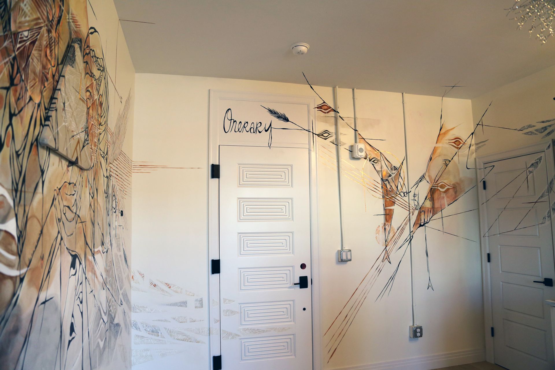 White room with abstract wall murals, a closed door, and sketch-like line art across the walls and ceiling