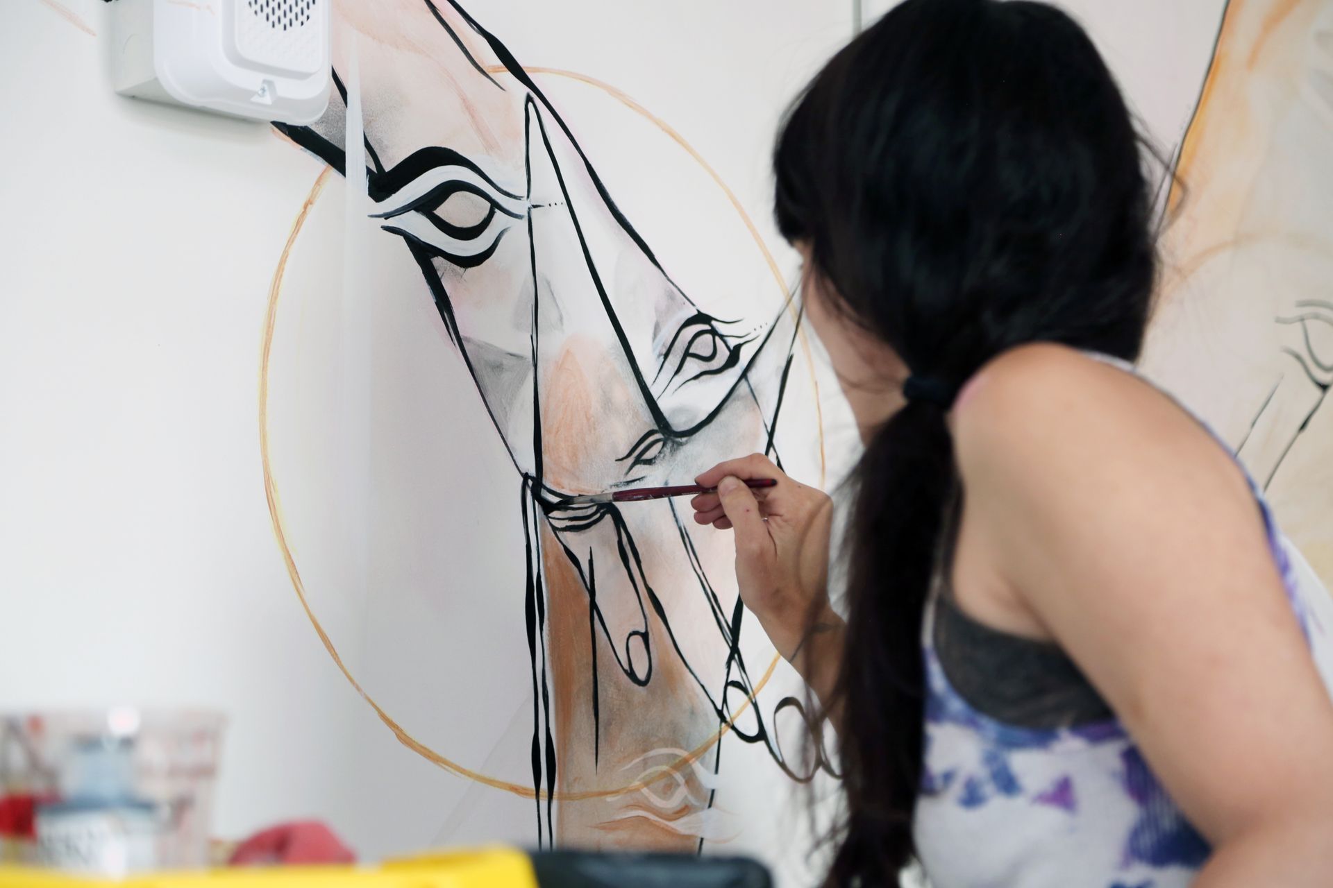 Artist painting a stylized horse mural on a wall