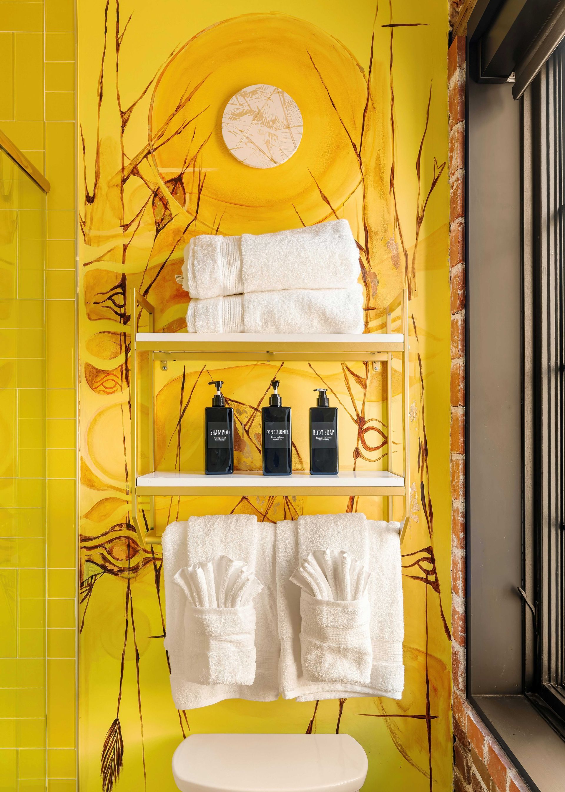 Yellow bathroom shelf with towels and toiletries against a bright patterned wall