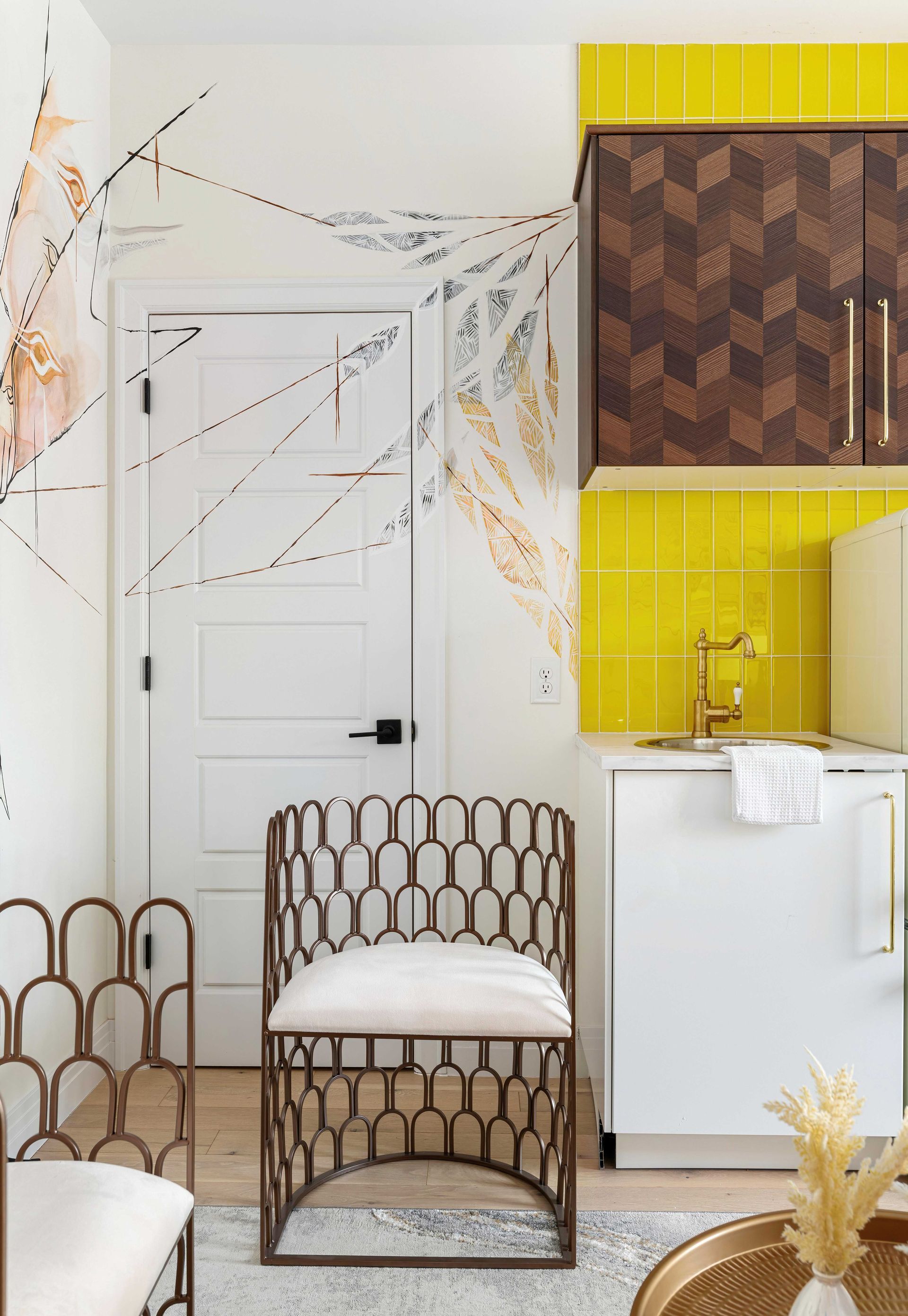 Stylish white room with patterned chair, yellow shelf, and modern cabinet against a decorated wall