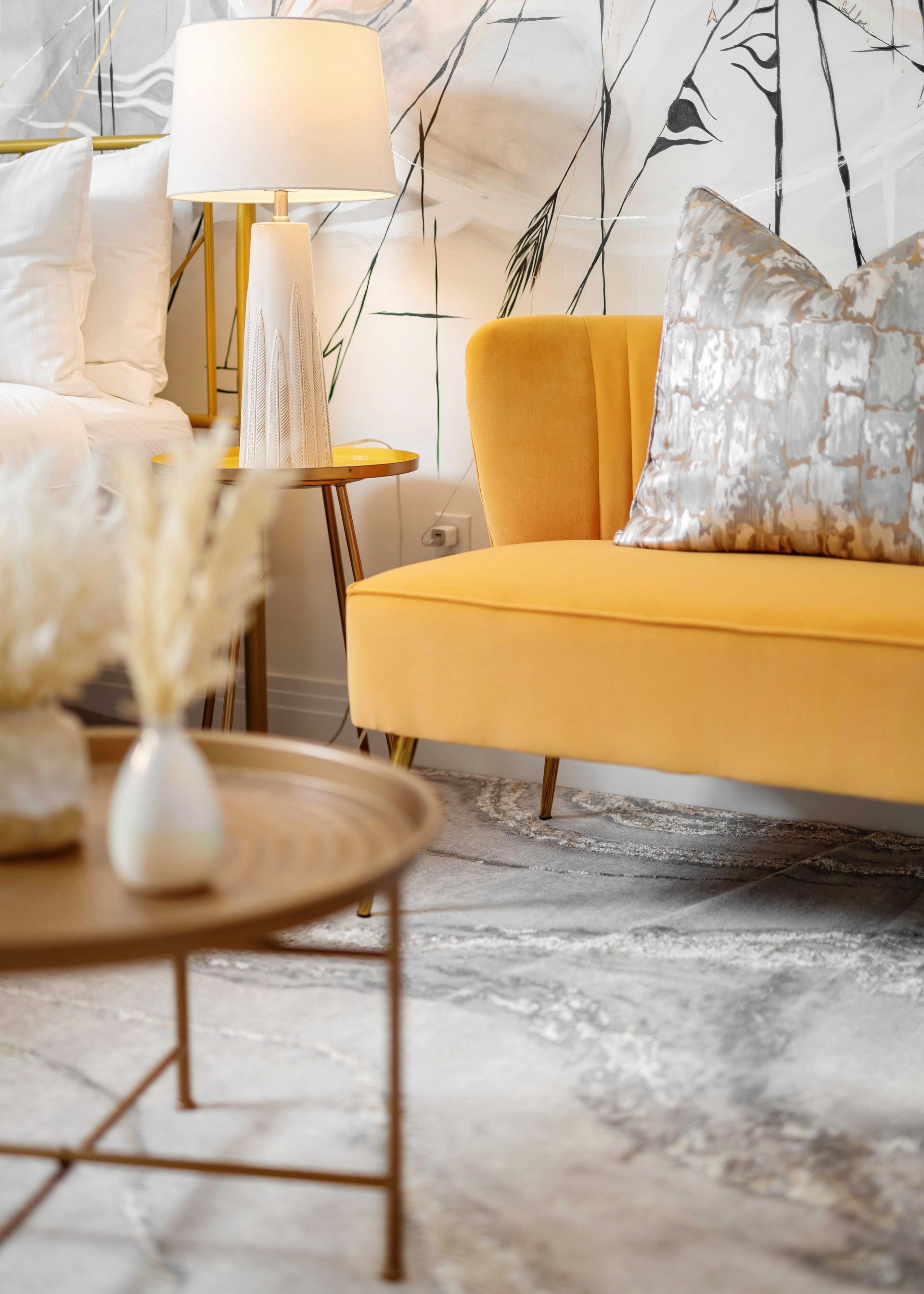 Modern living room with yellow sofa, white lamp, gold accents, and abstract wall art