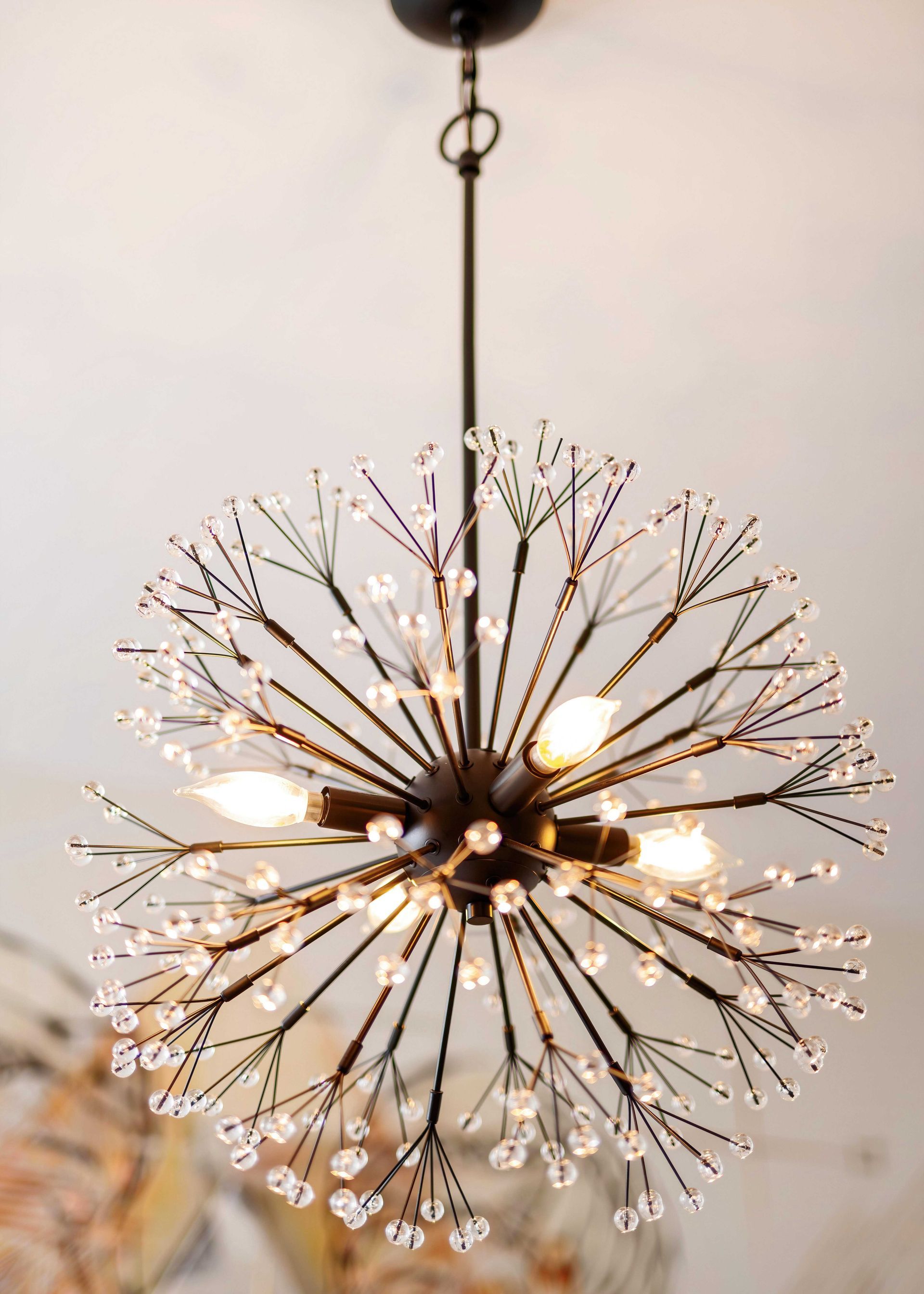 Modern globe pendant light with warm bulbs and delicate black wire spokes hanging from the ceiling