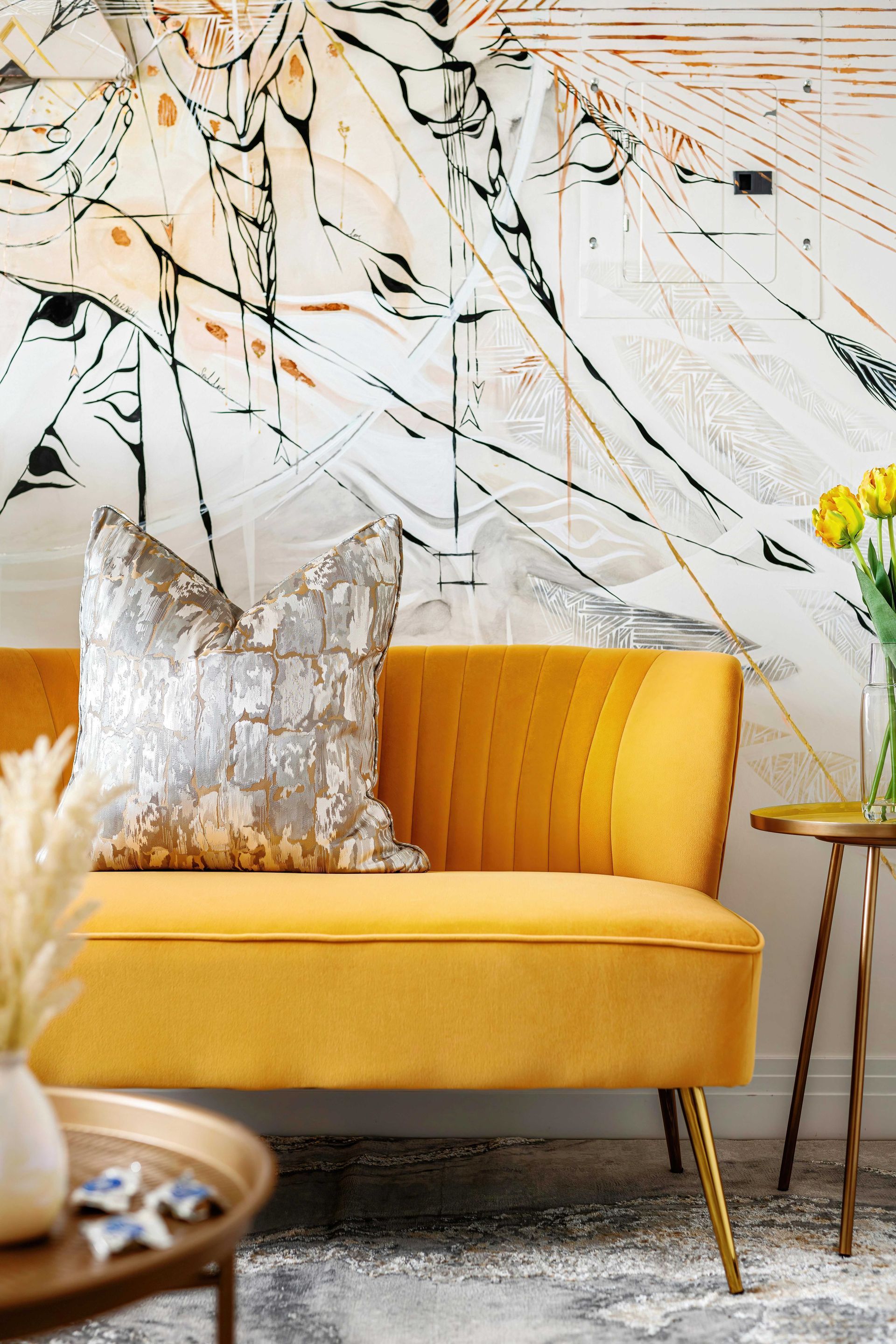 Yellow sofa with a silver pillow in a bright modern living room with abstract wall art
