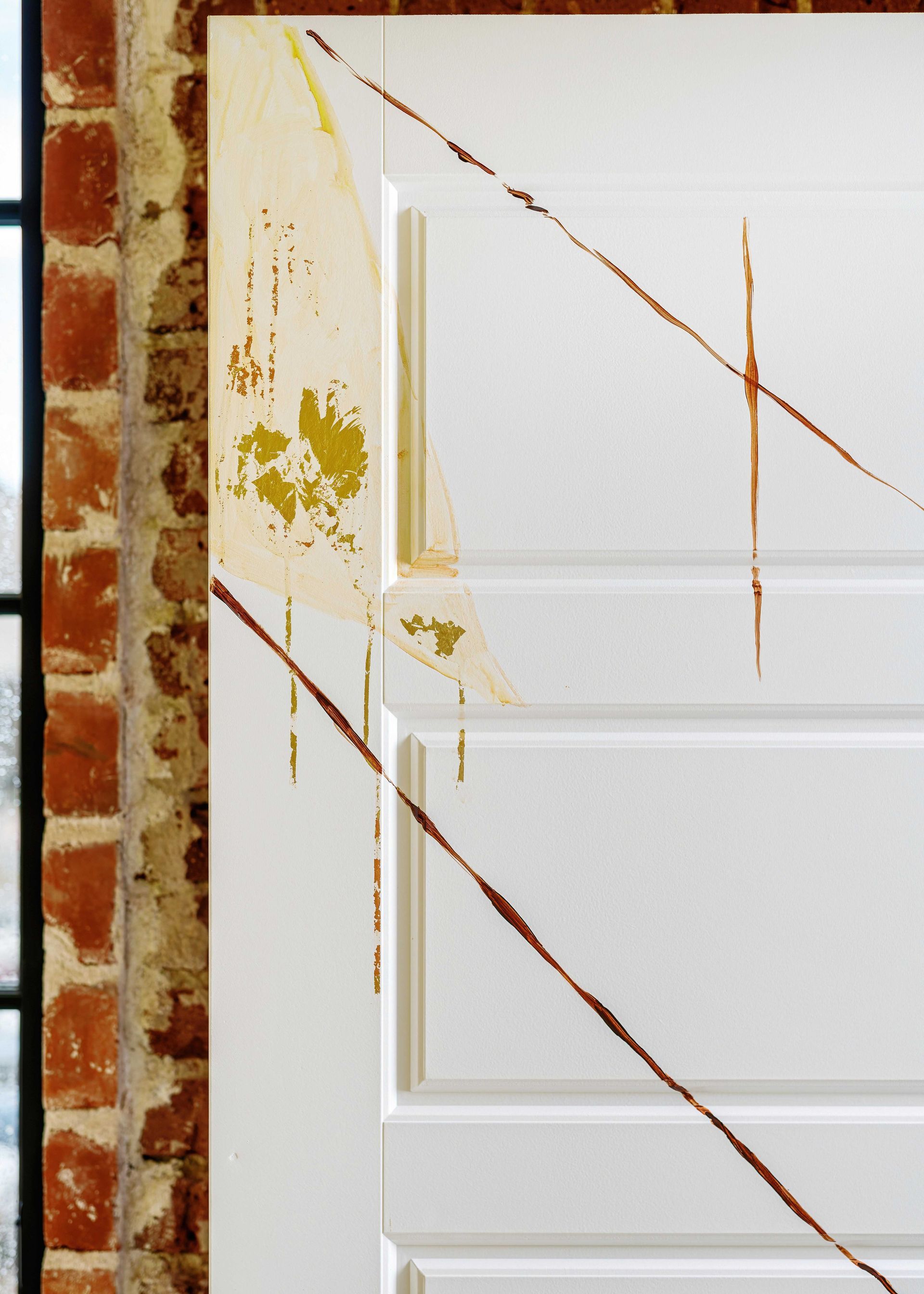White door panel with yellow-brown stains and a brick wall edge