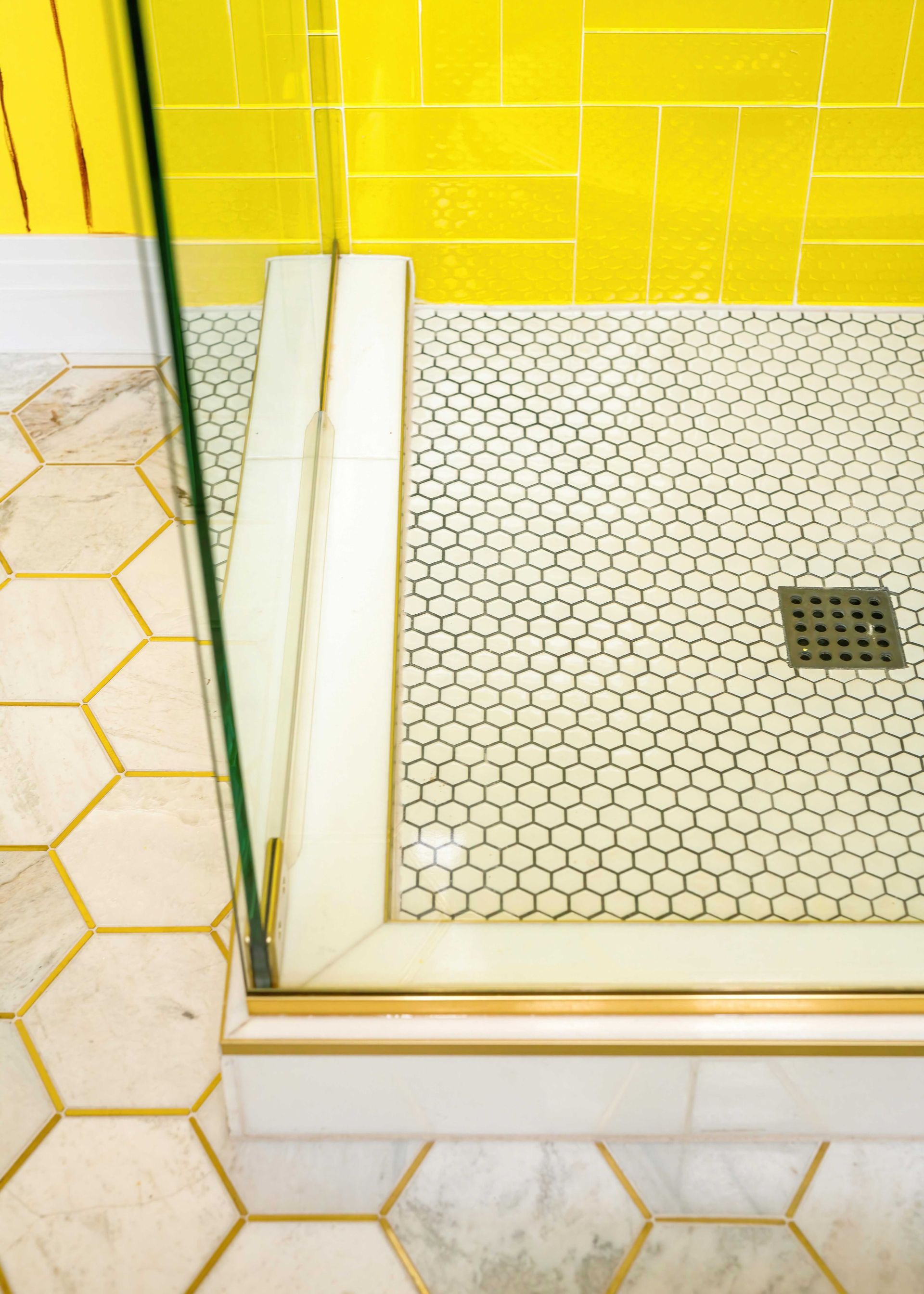 White-tiled shower corner with yellow wall tiles and a glass door frame