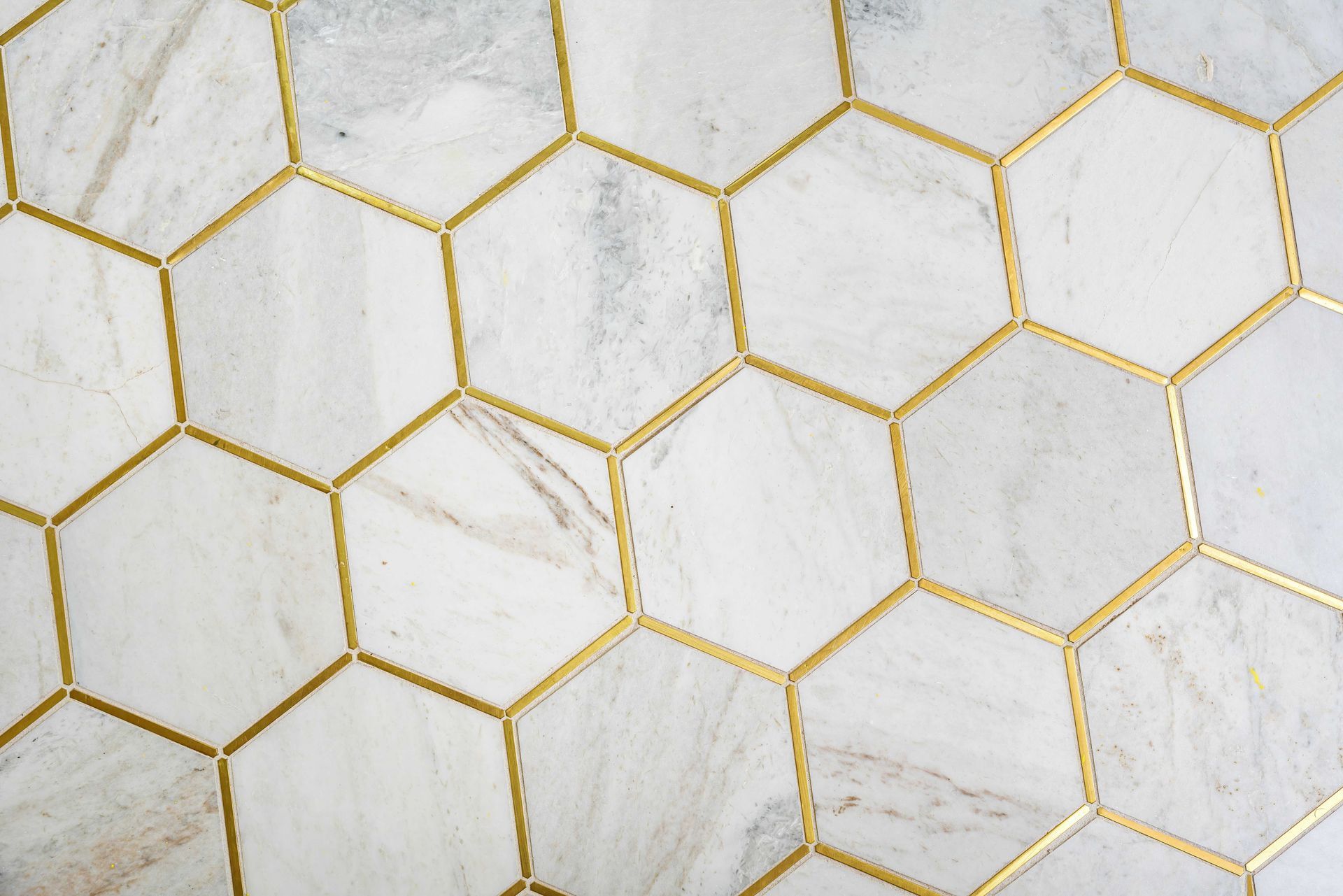 White marble-like hexagonal tiles with gold grout lines