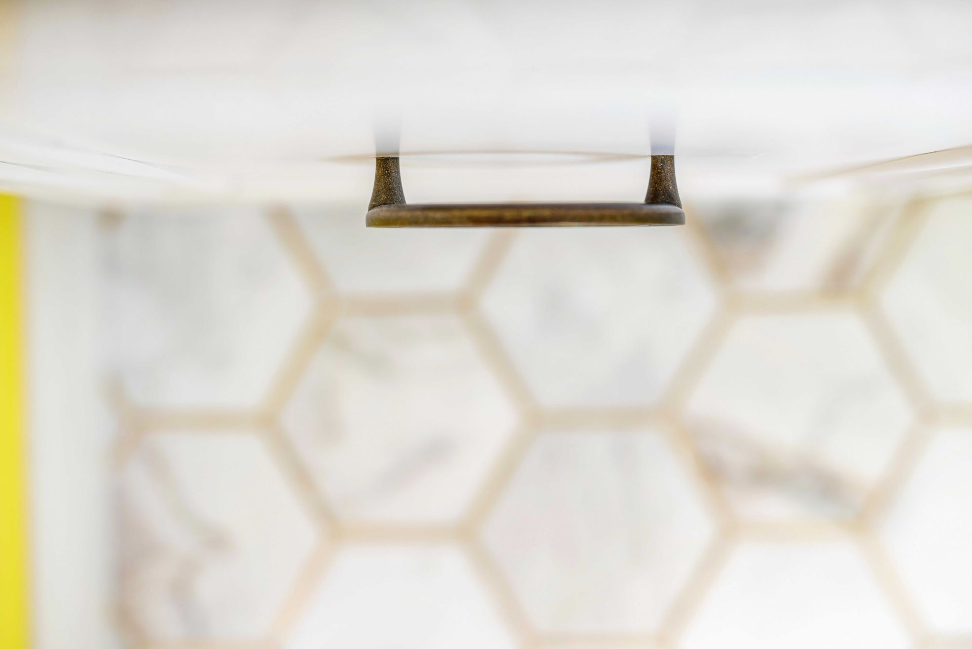 Close-up of a white ceiling vent with a blurred hexagonal tile pattern in the background