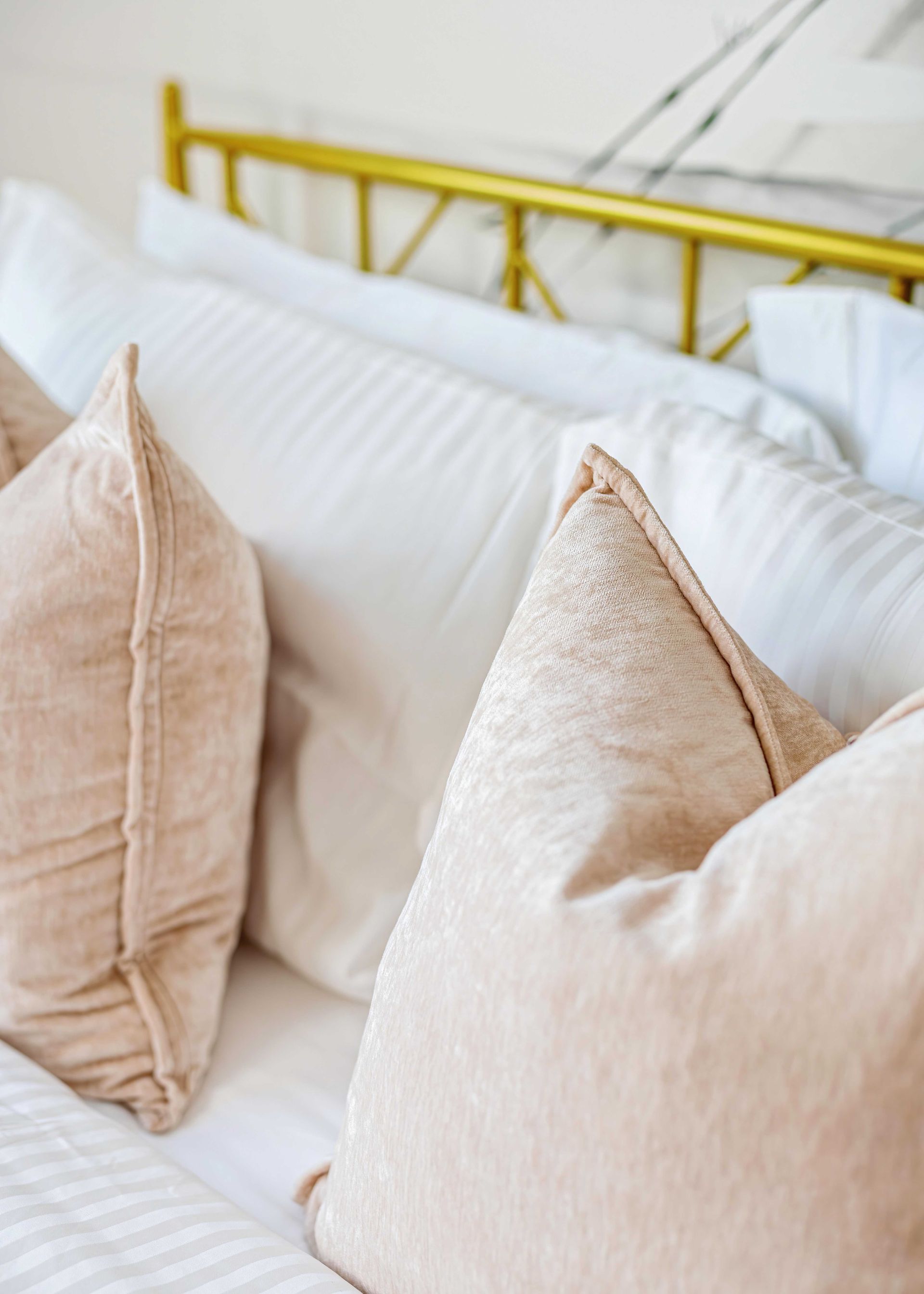 Beige throw pillows on a white sofa with a yellow metal headboard in the background