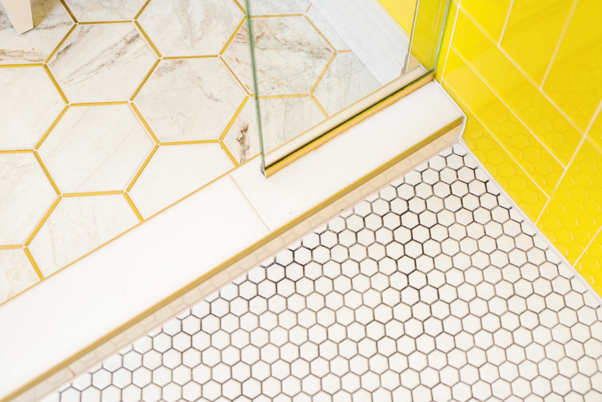 White and gold geometric tile flooring with a yellow-tiled corner and hexagonal mosaic tiles