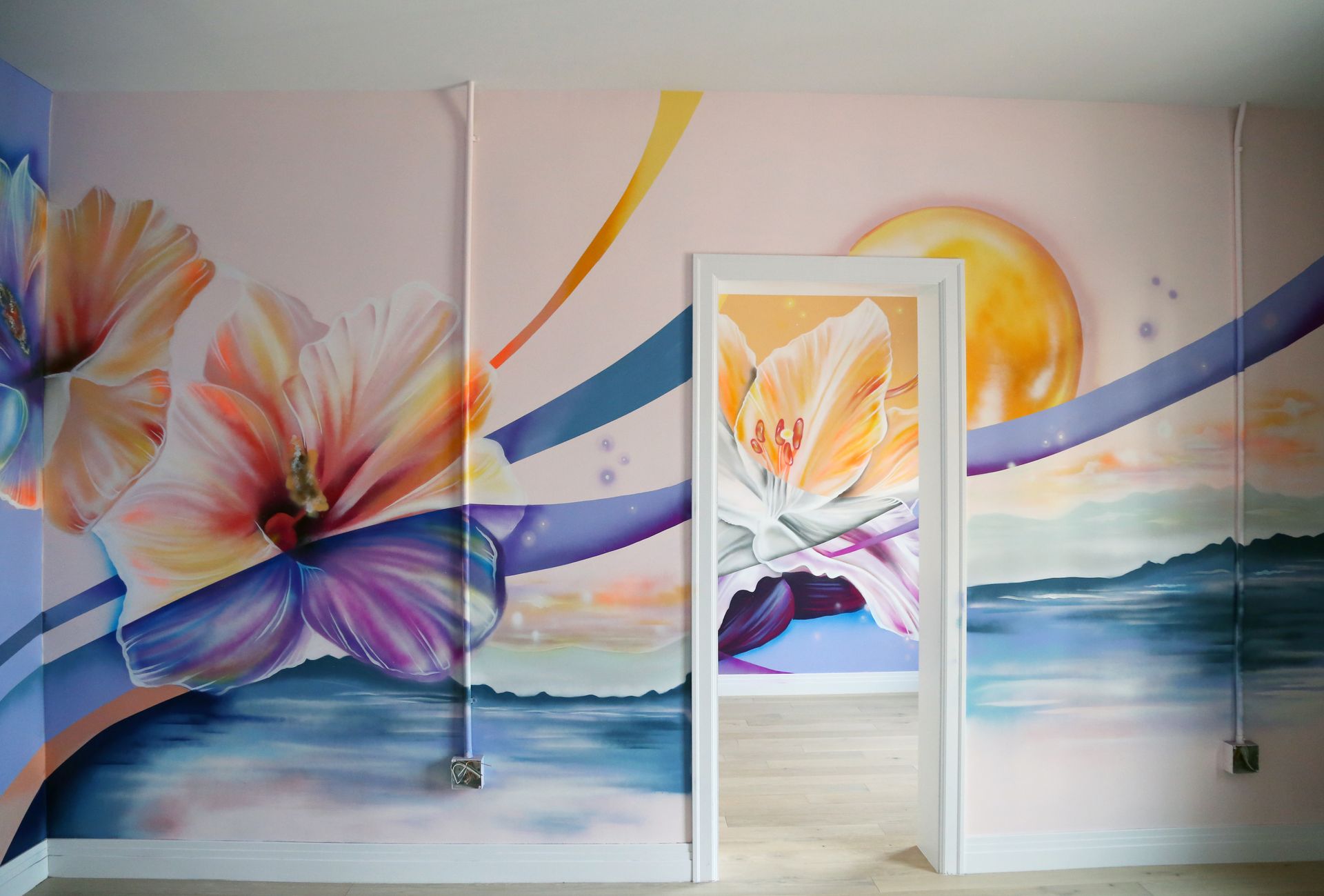 Colorful floral mural with blue waves and a bright sun around a central doorway in a room