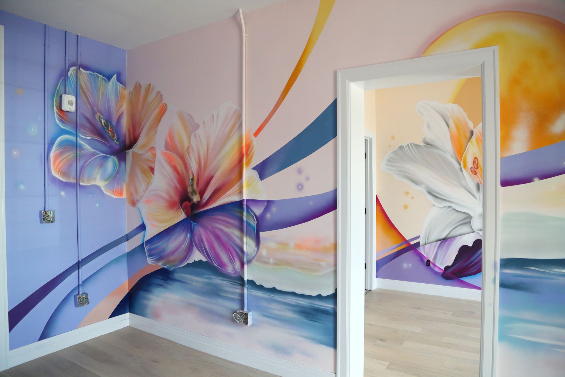 Colorful butterfly mural on pastel room walls, with an open door revealing matching wall art inside.