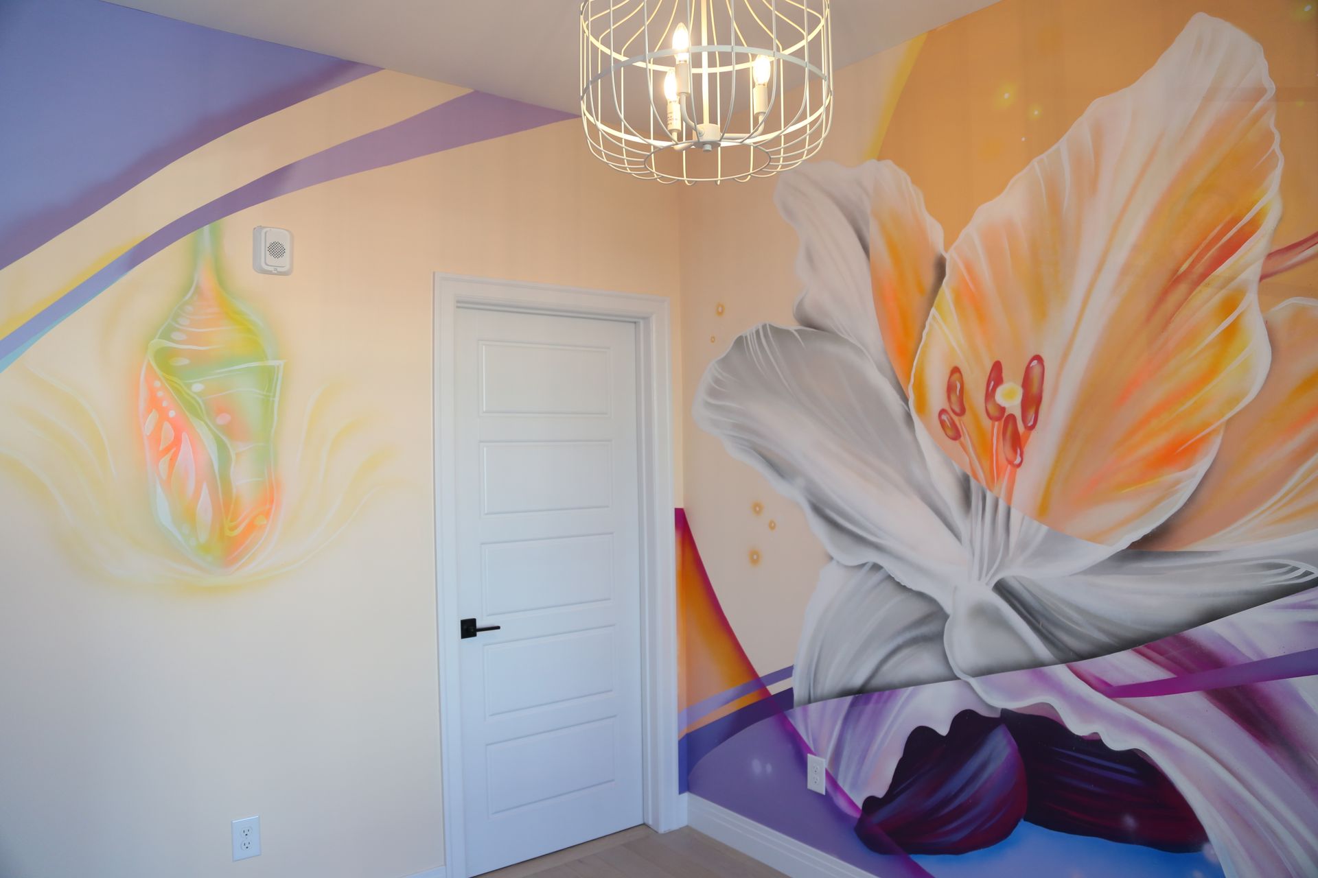 Bright room with a large white-and-orange flower mural on the wall and a white door.