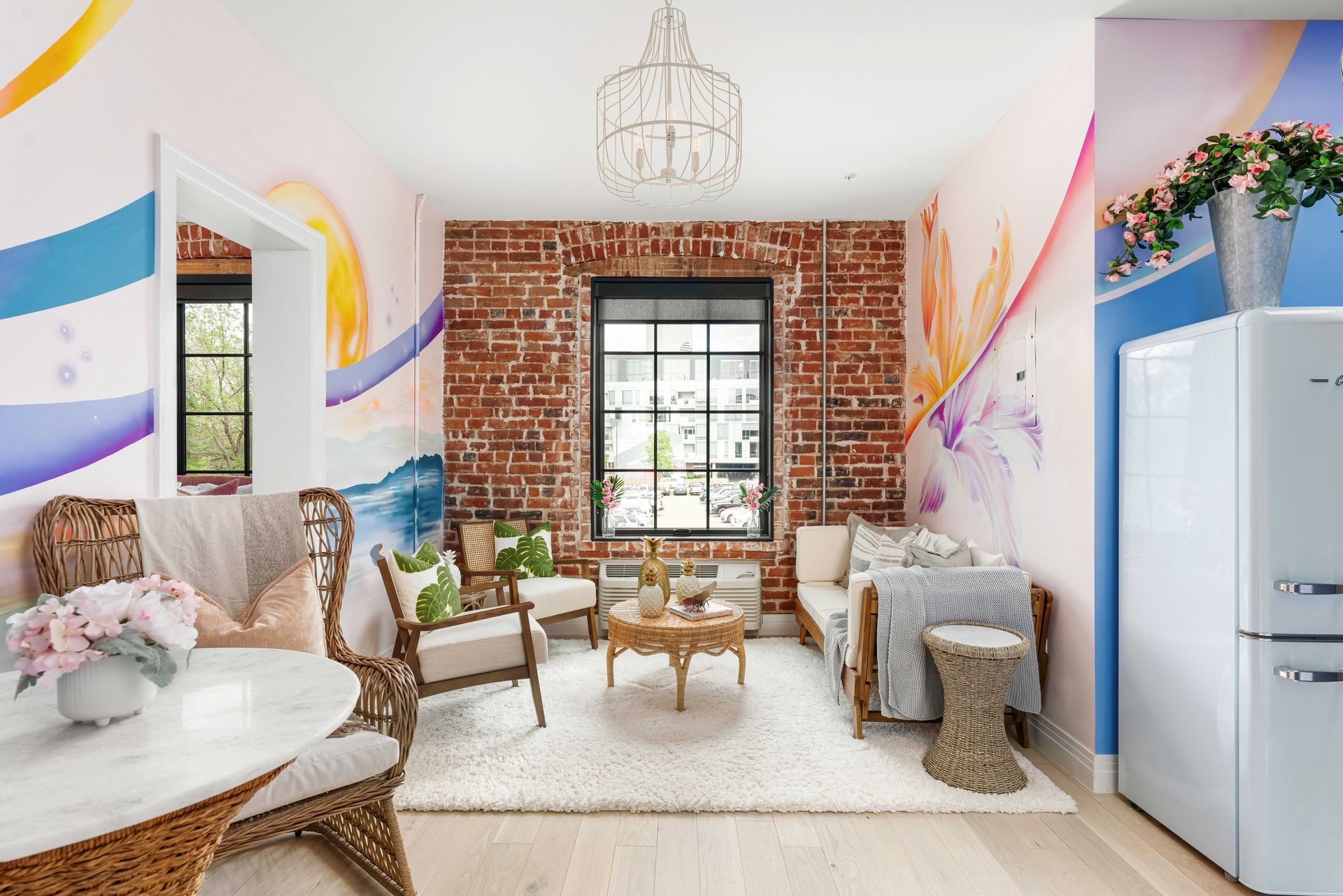 Bright eclectic living room with exposed brick, pastel wall art, white sofa, and window seat