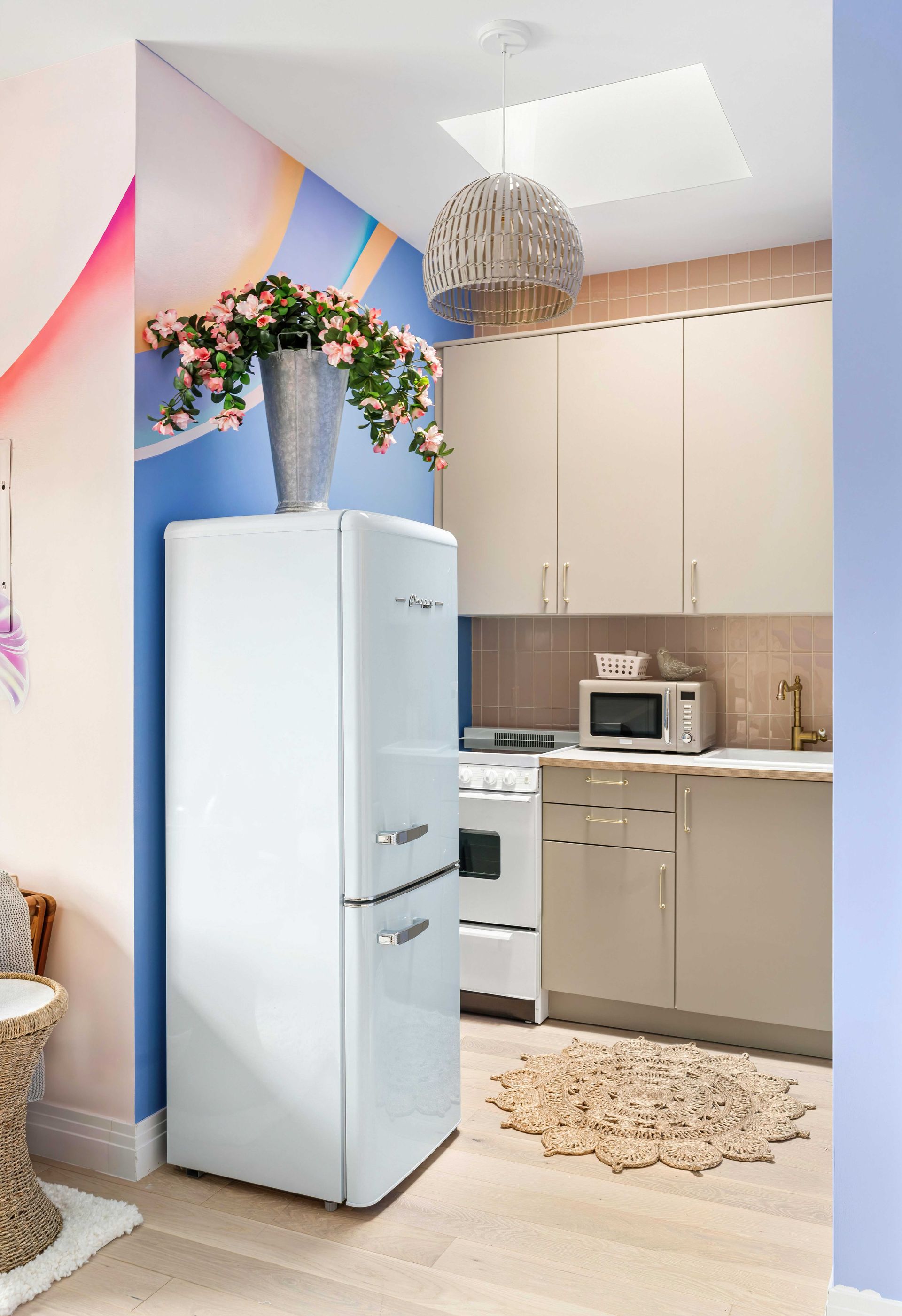 Small pastel kitchen with white fridge, beige cabinets, a microwave, and floral garland decor